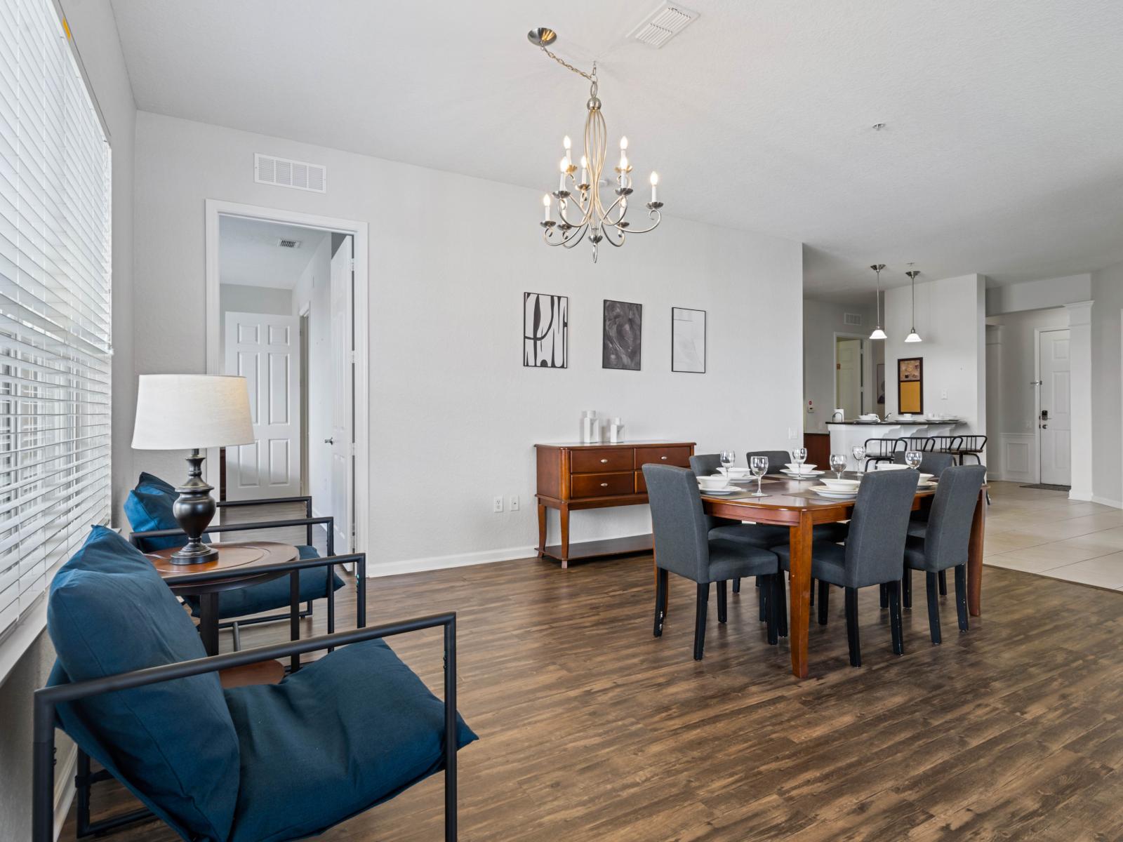 - Open dining area complemented by a cozy seating nook with stylish blue chairs - Tasteful decor, hardwood floors, & modern chandelier create a sophisticated atmosphere - Seamless connection to the kitchen and living areas for effortless entertaining