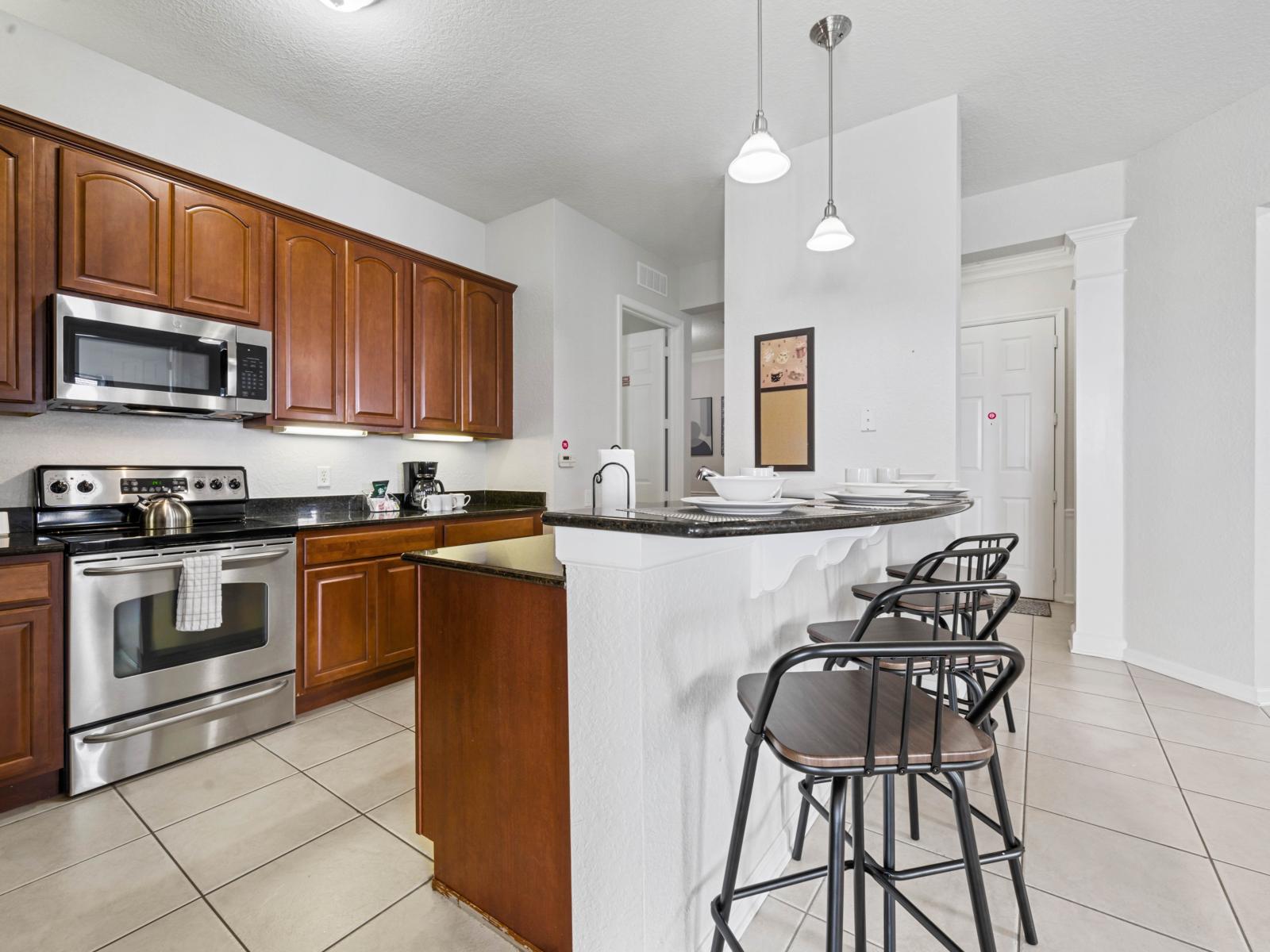 - Kitchen featuring stainless steel appliances, granite countertops, & warm wood cabinetry - Breakfast bar with stylish barstools is perfect for quick meals - Designed for both function & style, making meal preparation a breeze during your stay