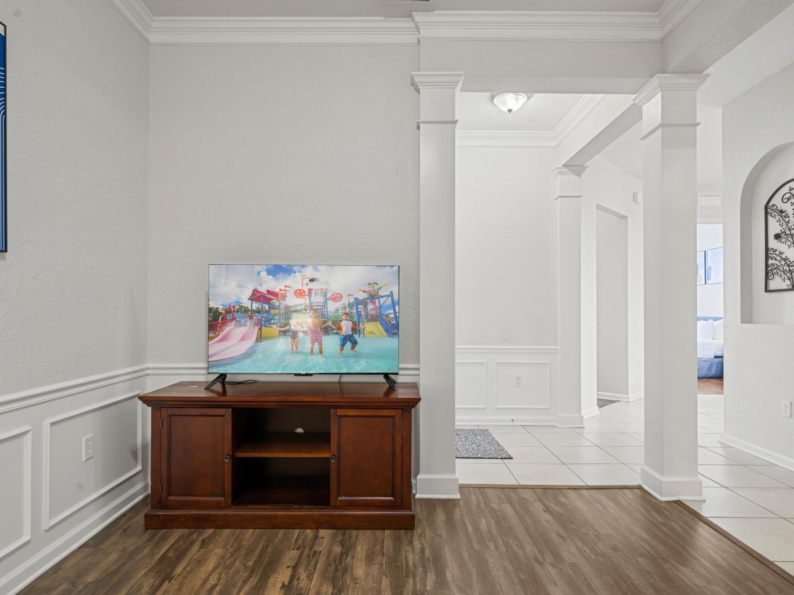 - Entertainment corner with a smart TV & classic wooden console, perfect for family movie nights - Located in a beautifully designed space with elegant wainscoting & hardwood floors - Thoughtfully positioned for a cozy & immersive viewing experience