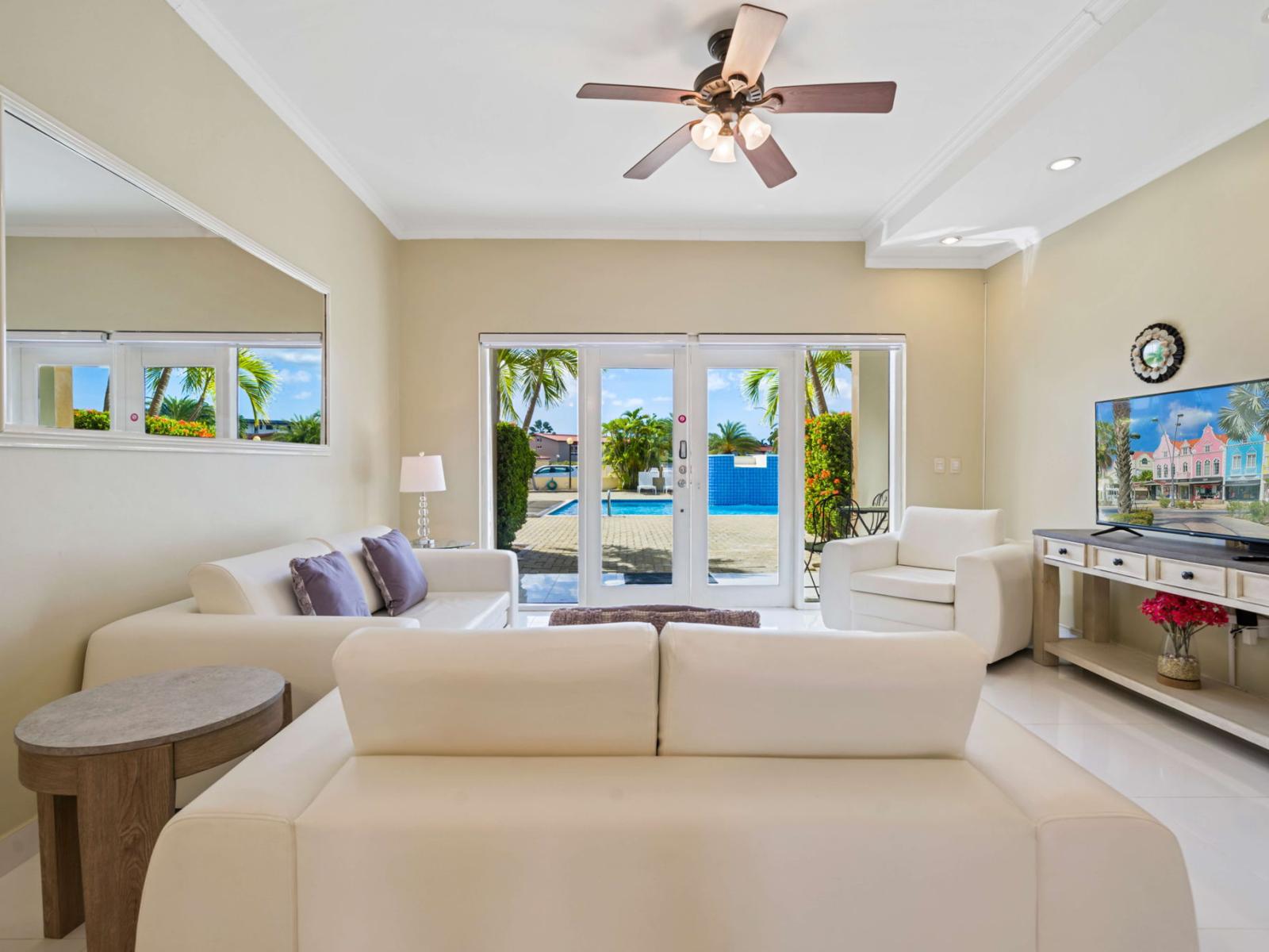 Relax in this bright and inviting living area, featuring cozy seating, a smart TV, and direct access to a serene private pool and lush tropical views – the perfect retreat for your next vacation.