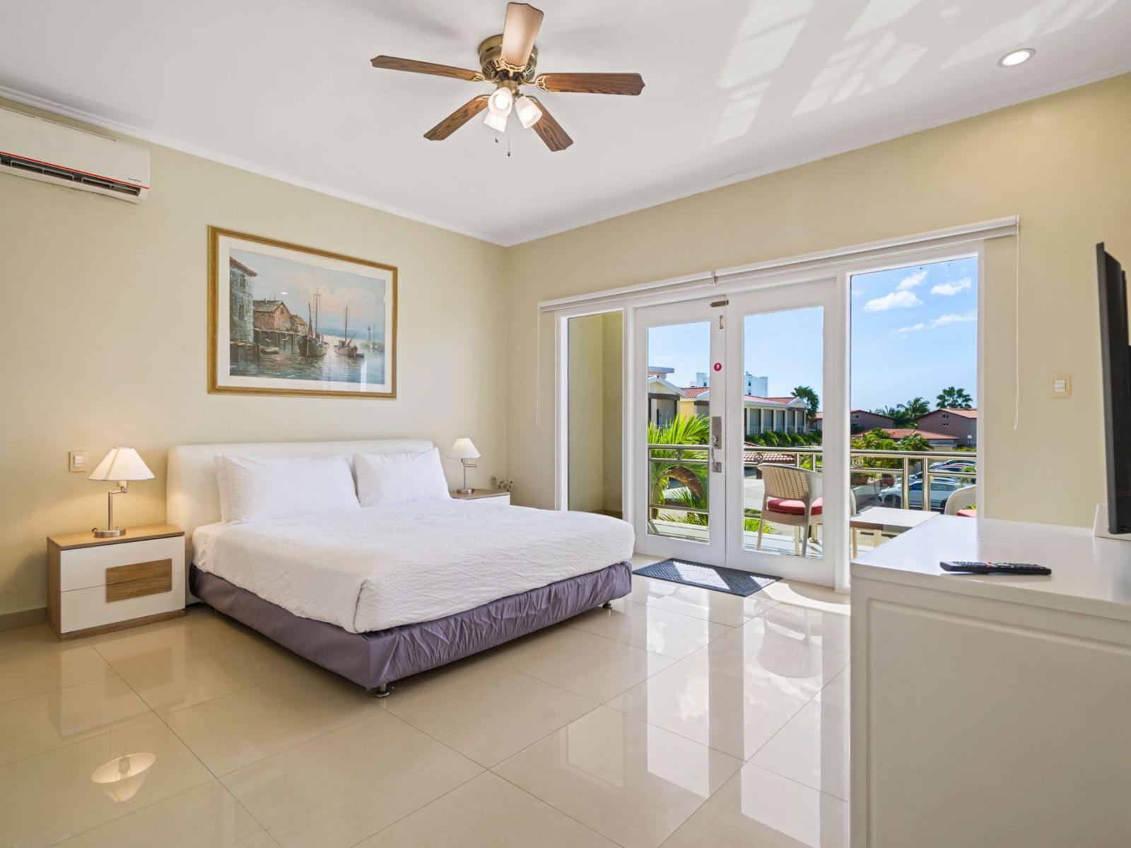 Wake up to stunning tropical views in this spacious bedroom, featuring a plush king bed, private balcony access, and a flat-screen TV for ultimate comfort and relaxation.