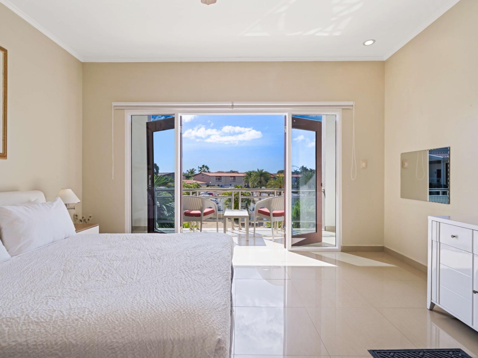 Wake up to stunning tropical views in this spacious bedroom, featuring a plush king bed, private balcony access, and a flat-screen TV for ultimate comfort and relaxation.