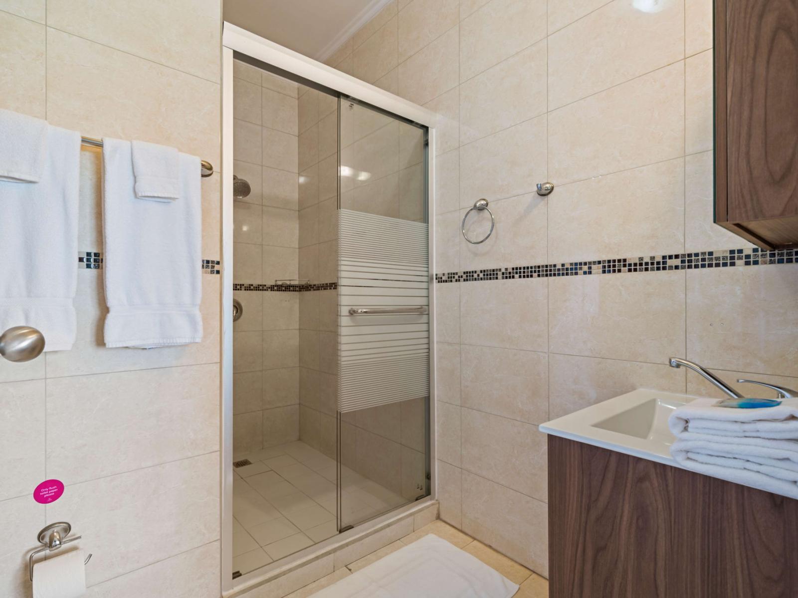 Private ensuite in the second bedroom with a walk-in shower, sleek sink, and modern toilet – a perfect blend of comfort and convenience for your Airbnb stay!