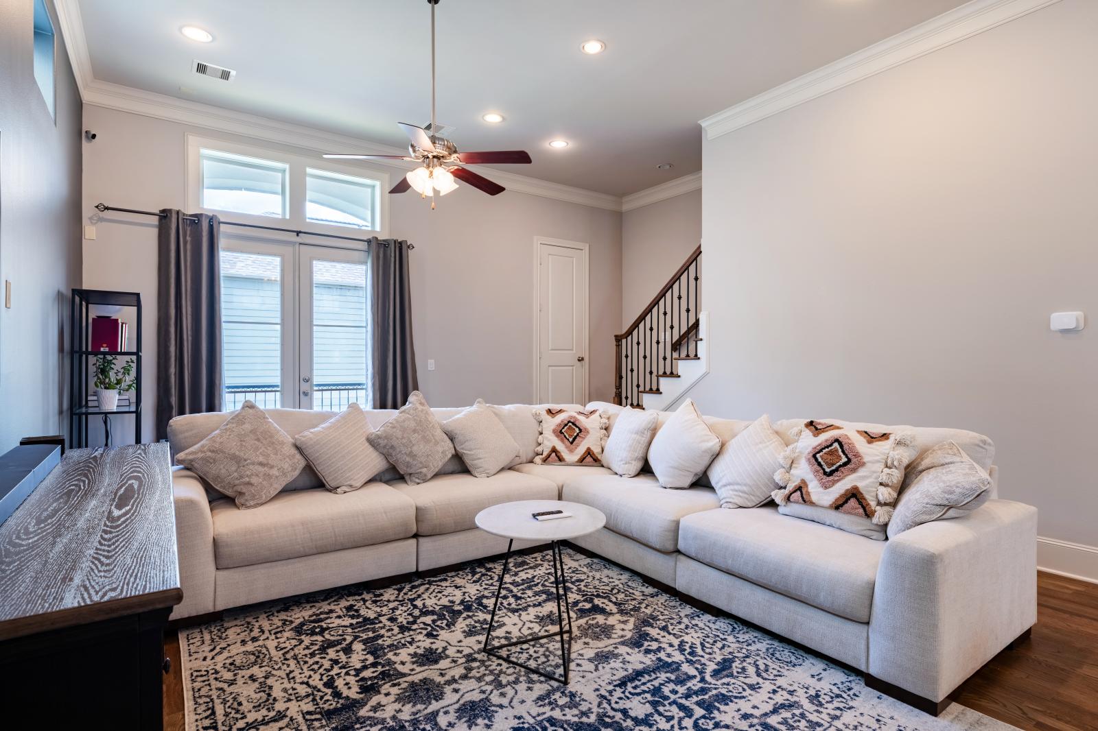 2nd-floor living room featuring a plush sectional, natural light, high ceilings, and direct balcony access—perfect for unwinding.