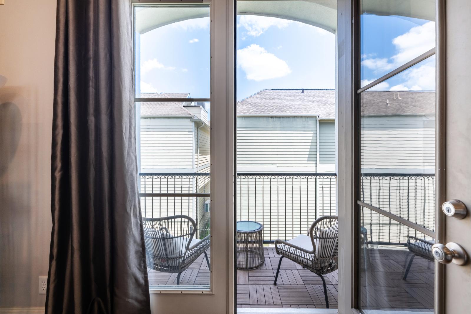 French doors from the main living room lead to a cozy balcony featuring stylish seating for two—perfect for morning coffee or evening wine.