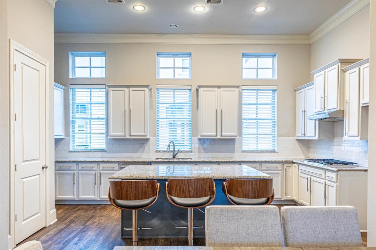 Ample natural light from large windows enhances the elegant and inviting atmosphere—ideal for cooking or socializing.