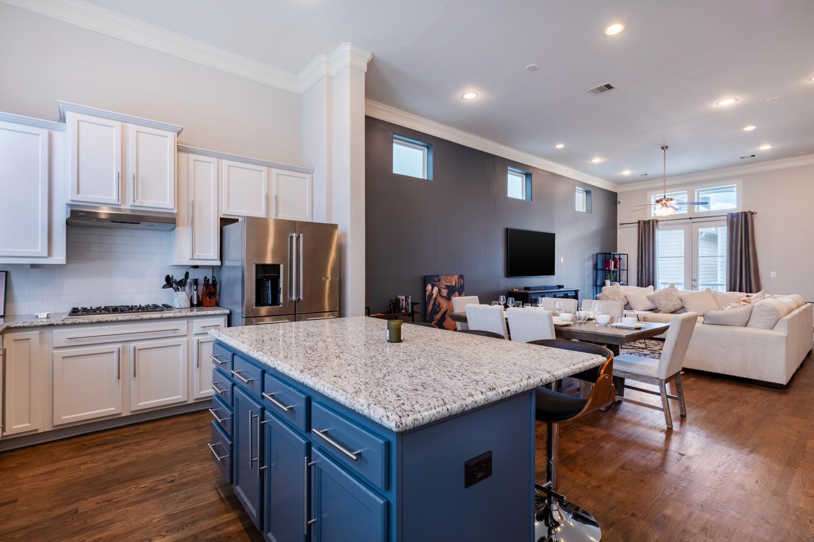 Island kitchen with sleek granite counters, bright cabinetry, high-end appliances, stylish seating, and ample natural light from large windows enhance the elegant and inviting atmosphere - ideal for cooking or socializing!