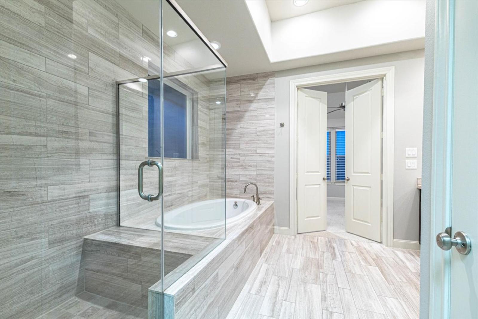 The main bathroom on the 3rd-floor features a spacious glass-enclosed shower, soaking tub, and modern finishes. The elegant tilework and soft lighting create a spa-like retreat, perfect for unwinding after a day of exploring!