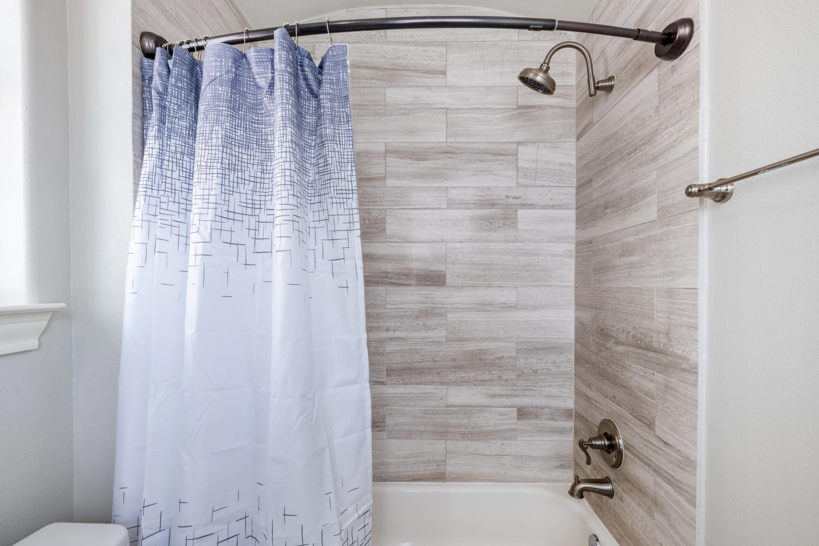 A relaxing tub/shower combo with wood-look tiles is perfect for comfort & privacy.
