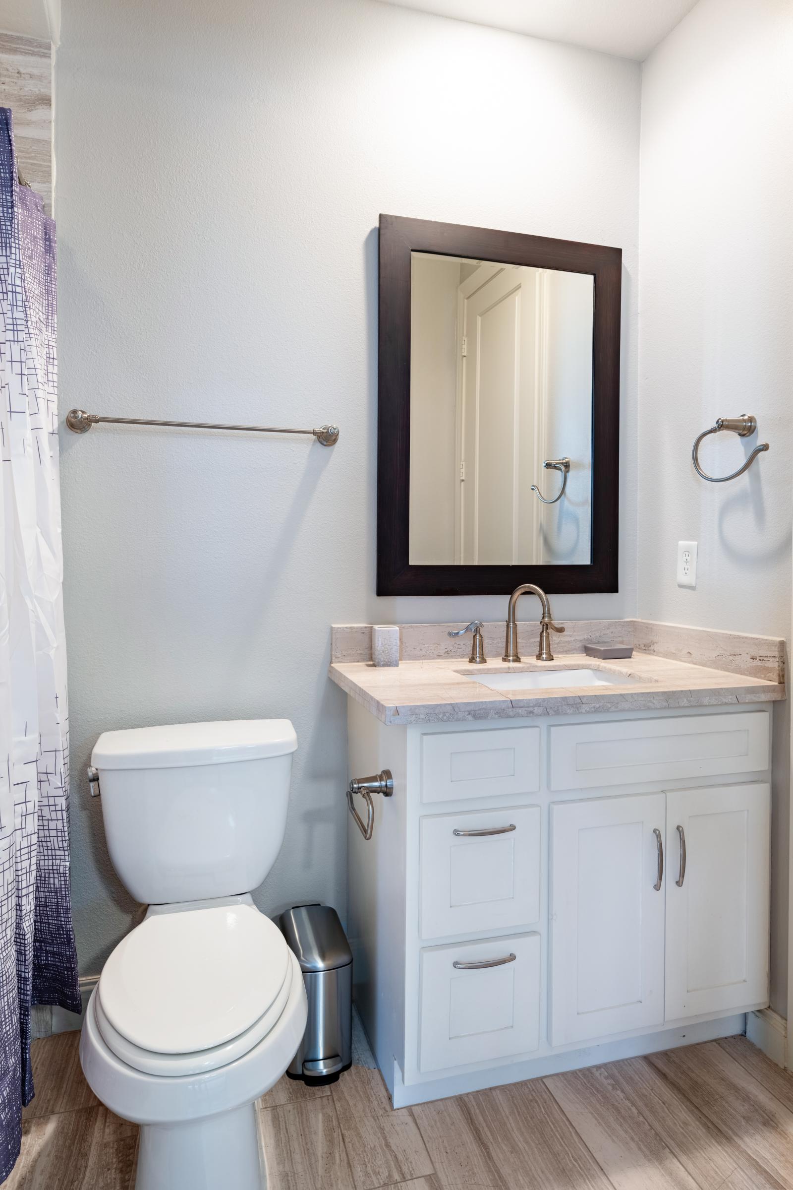 Stylish Bedroom 3 en-suite on  3rd-floor featuring a sleek modern bathroom with elegant wood-look tiles, a bright vanity, and a relaxing tub/shower combo. Perfect for comfort & privacy.