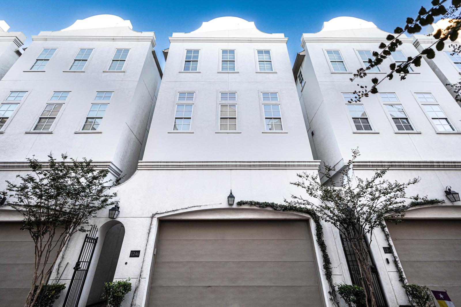 3-story townhome featuring a sleek white stucco exterior, elegant architecture, a spacious 2-car garage, with large windows that flood the space with natural light. A stylish retreat in the city!
