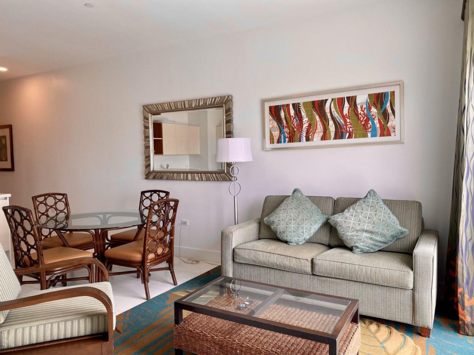 Stylish living space with a comfortable sofa, elegant decor & a cozy atmosphere - Thoughtfully designed with warm accents, a large mirror & vibrant artwork - Perfect for unwinding after a long day, whether you’re relaxing with a book or watching TV