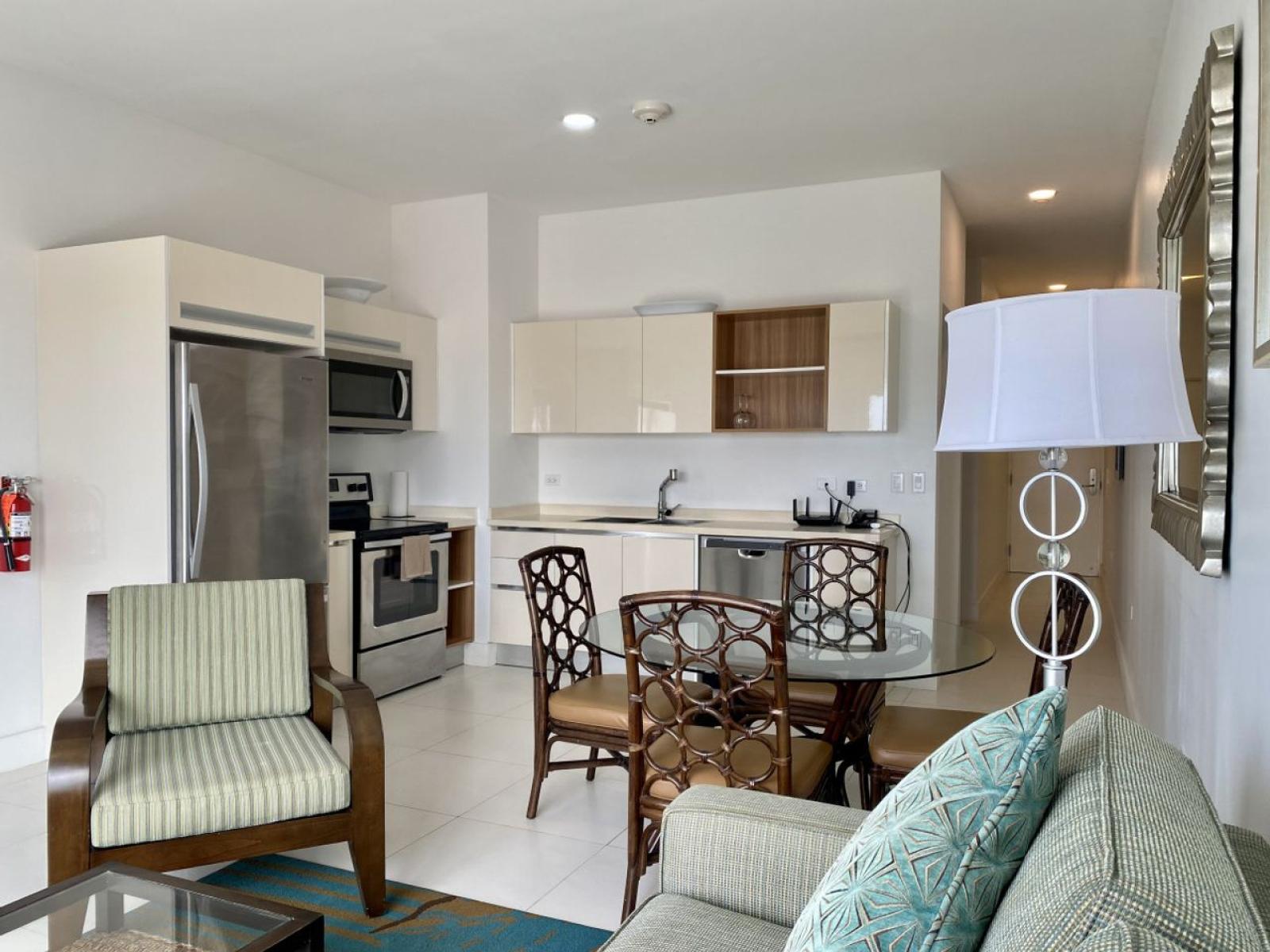 Open concept kitchen featuring sleek stainless steel appliances & counter space - Cozy dining area with a glass top table is ideal for enjoying meals or gatherings - Seamless flow between the kitchen & living space creates a  welcoming environment