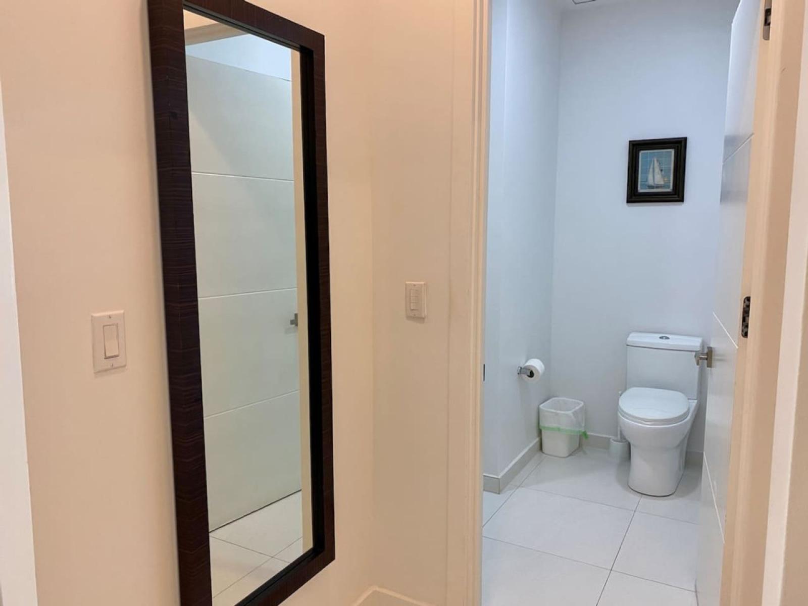 Bright hallway leading to a well maintained bathroom for added convenience - Full length mirror adds both functionality & style, perfect for getting ready before heading out - Minimalist design with modern touches ensures a fresh & inviting space