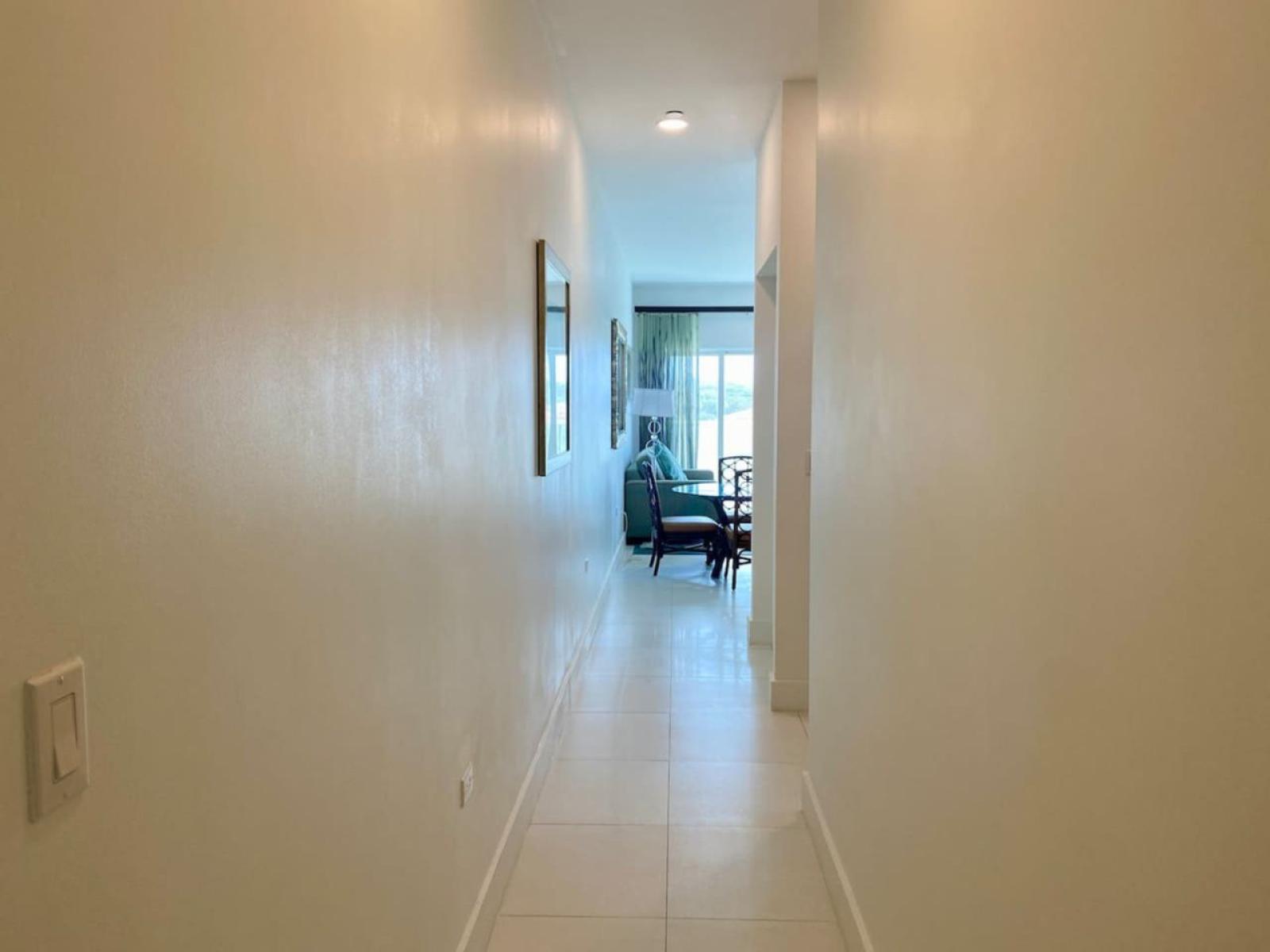 Bright and inviting hallway that leads to the heart of the home - Open layout creates a seamless flow, guiding you toward the cozy living and dining space - Modern, minimalist design with soft lighting makes every arrival feel warm and welcoming