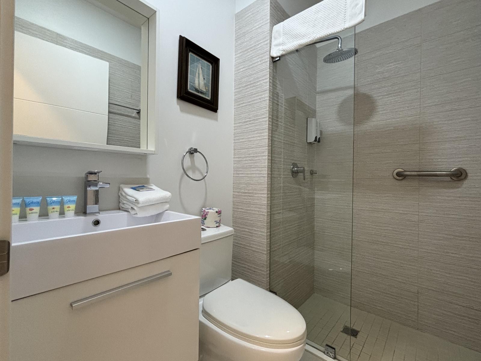 Unwind in a sleek, modern bathroom, designed for relaxation and comfort - Enjoy a refreshing rainfall shower, enclosed in elegant glass for a spa like feel - Bright, spotless, and stocked with essentials, offering a hotel style experience