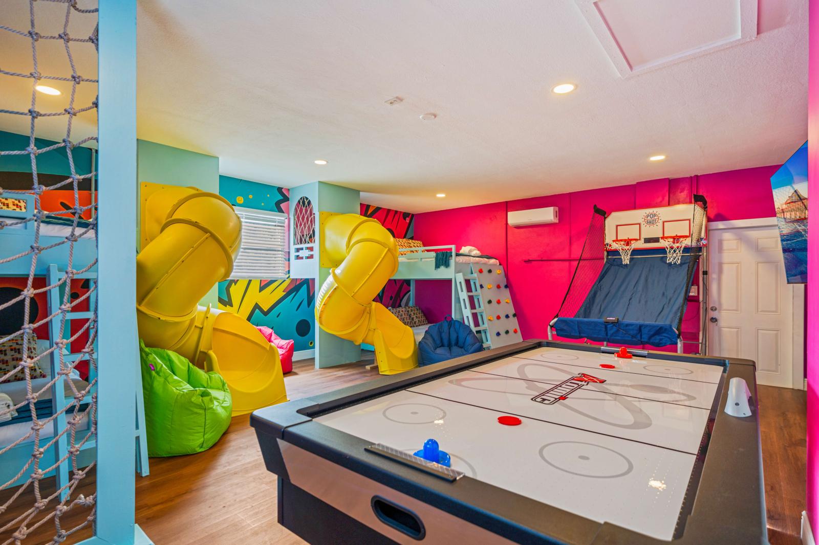 Ultimate kids' paradise featuring two double-over-double bunk beds with a slide, a fun climbing wall, an exciting air hockey table, and a thrilling basketball game