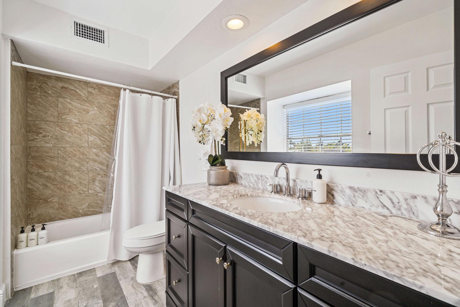 Spacious primary bathroom featuring a shower/tub combination, a modern toilet, and a generous vanity with ample counter space.