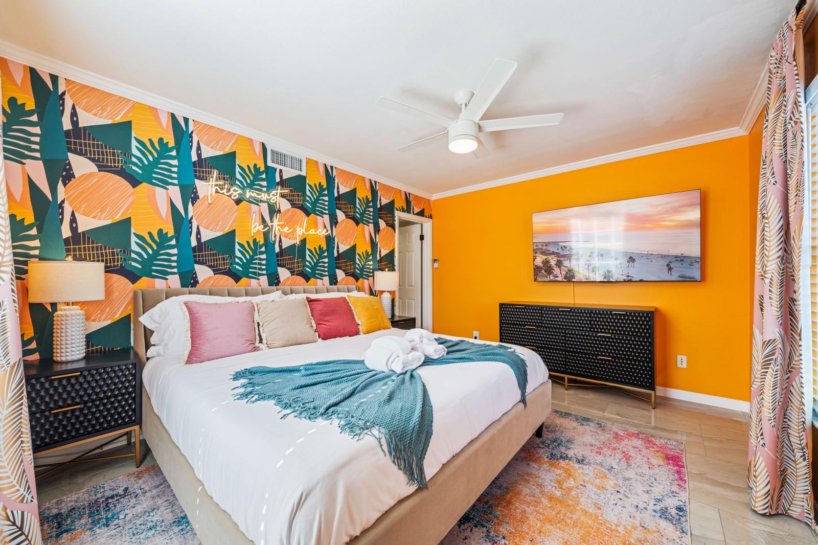 Bedroom 2: Ground-floor bedroom featuring a king-size bed, en-suite bathroom, a refreshing ceiling fan, and a large 65" smart TV for ultimate comfort and convenience.