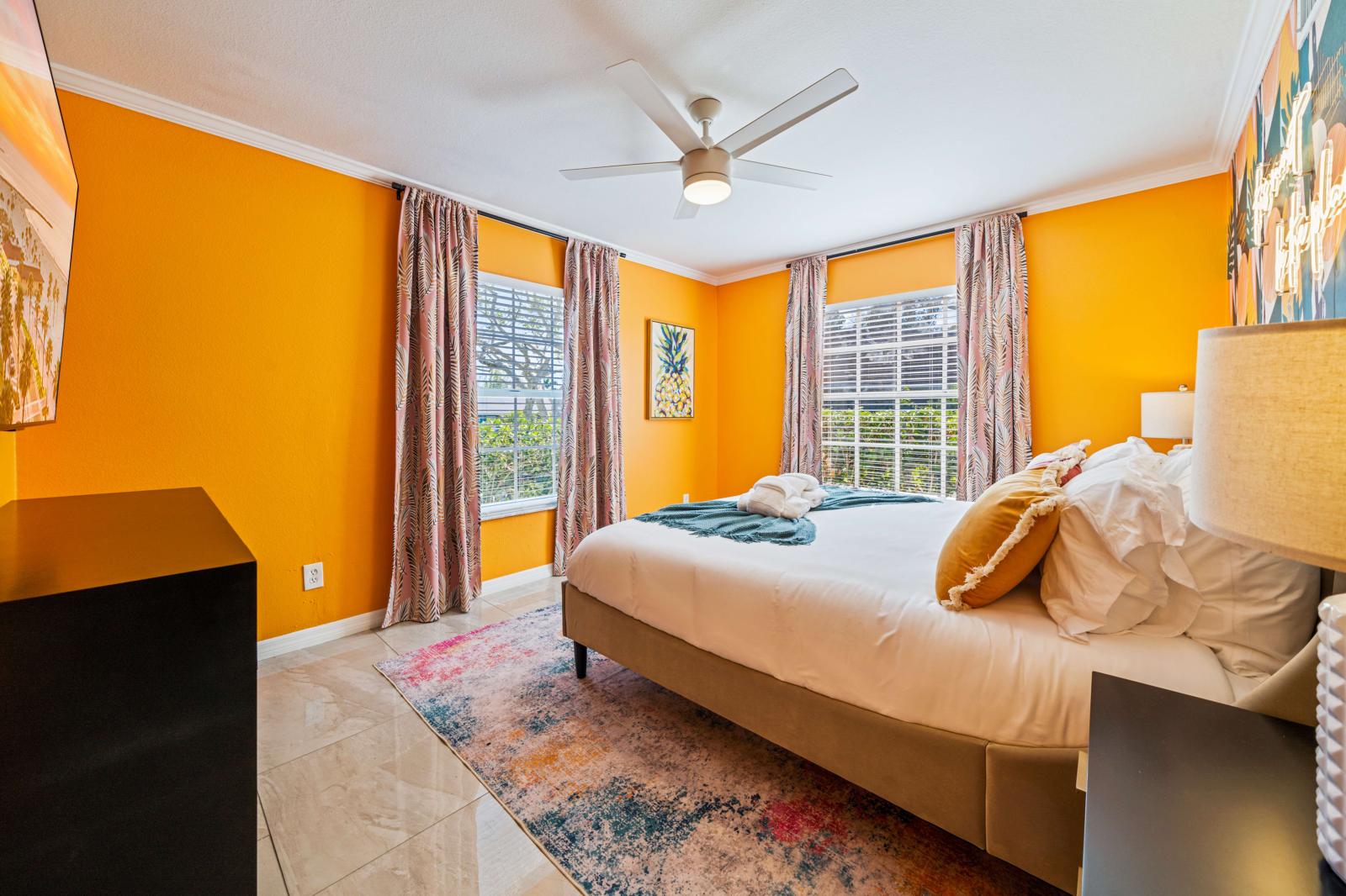 Bedroom 2: Ground-floor bedroom featuring a king-size bed, en-suite bathroom, a refreshing ceiling fan, and a large 65" smart TV for ultimate comfort and convenience.