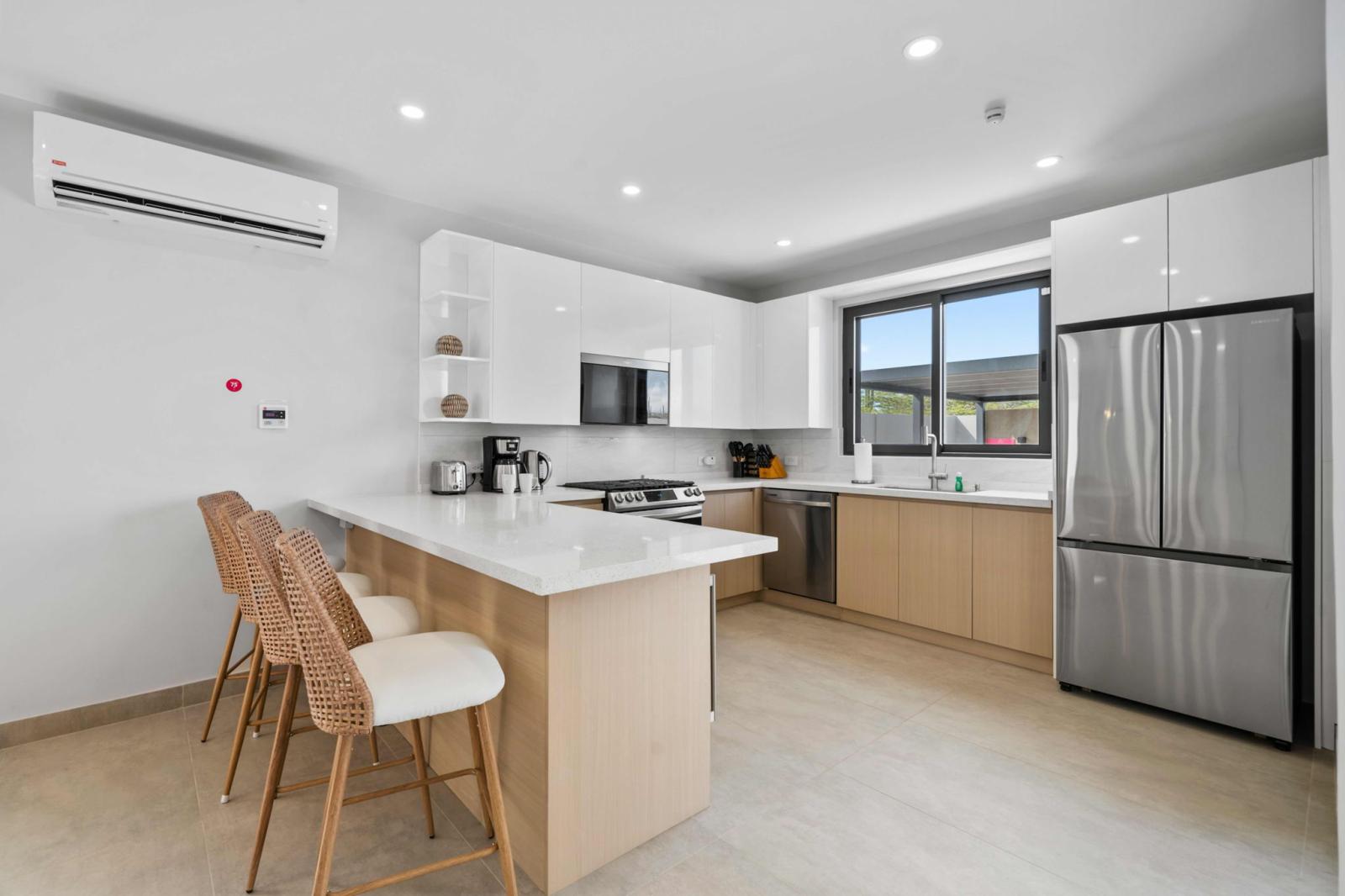 Modern kitchen fully equipped with stainless steel appliances for easy meal prep - Spacious countertops & a breakfast bar with cozy seating create a perfect gathering spot - Natural light & sleek design make this space inviting for cooking