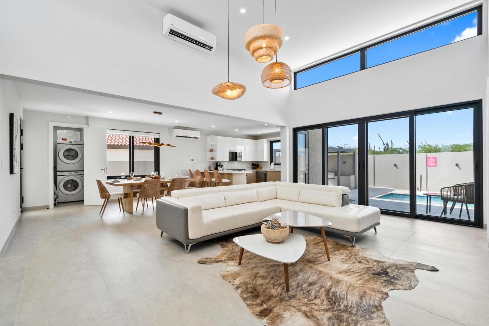 Bright, airy living room with high ceilings & a seamless outdoor connection - Cozy sectional, stylish accents, and natural textures create a welcoming retreat - Enjoy easy access to the pool and patio, perfect for unwinding after a day of exploring