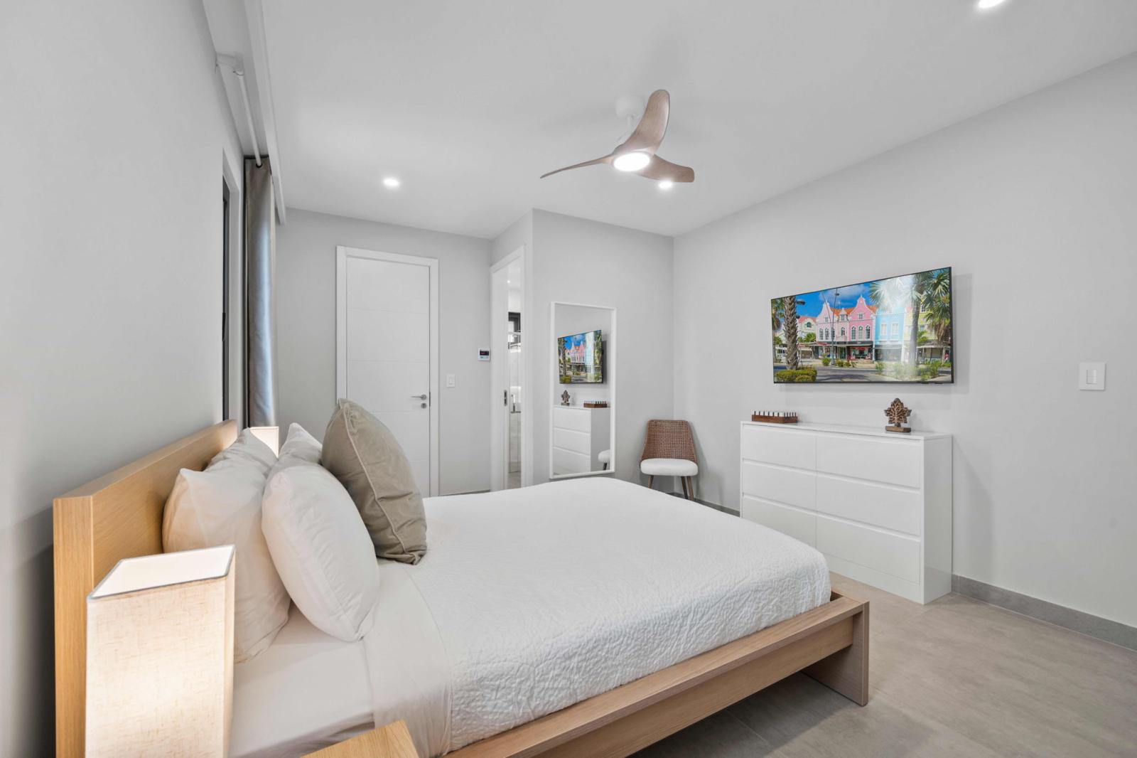 Cozy bedroom with a queen size bed, soft lighting & stylish neutral decor - Enjoy entertainment with a smart TV, or relax in the peaceful ambiance of this retreat - Thoughtful touches like a ceiling fan, dresser & mirror add comfort to your stay