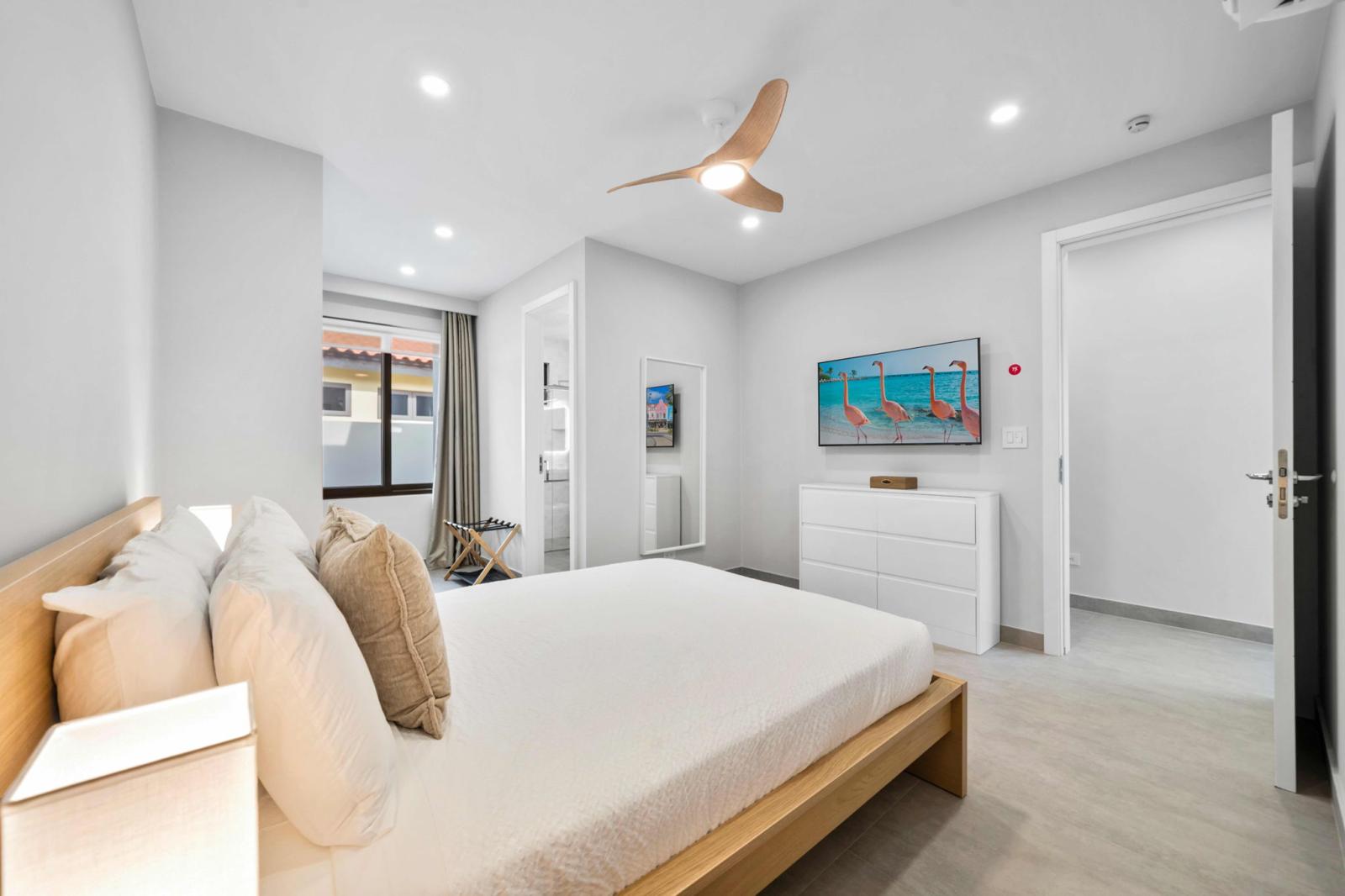 Cozy bedroom, featuring a plush queen size bed & soft linens for comfort - Unwind with the flat screen TV or enjoy a peaceful evening in this stylish retreat - Spacious dresser, ceiling fan & warm lighting create the perfect setup for a stay