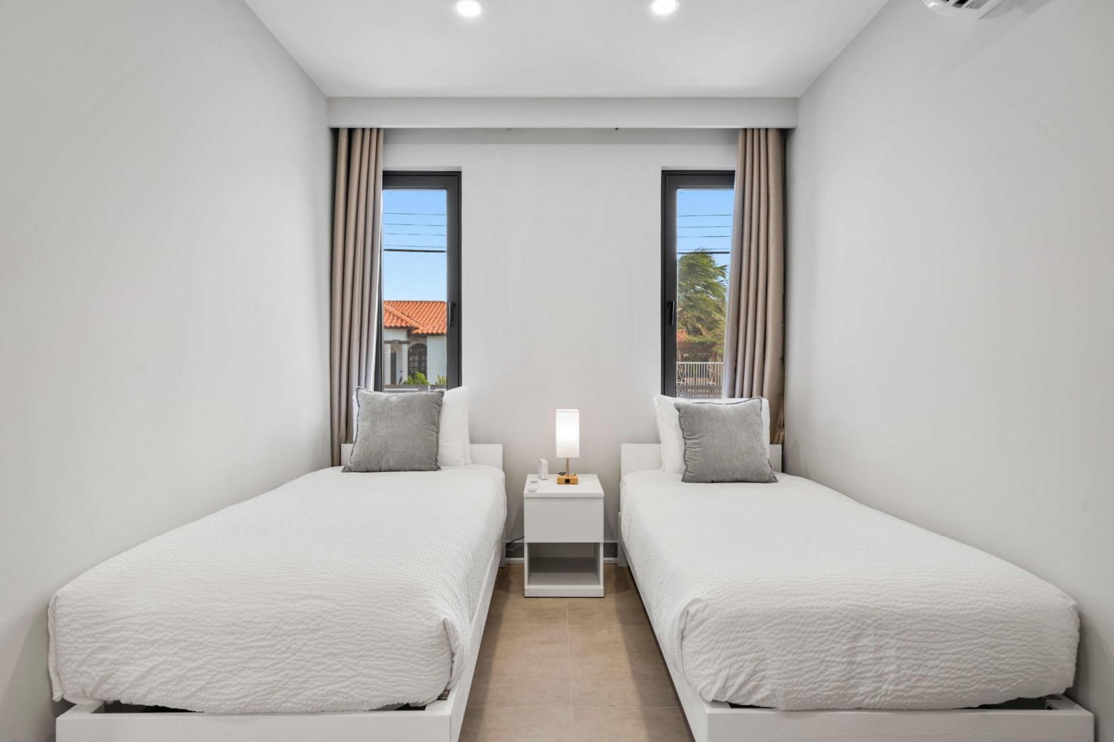 Bright & cozy twin bedroom, perfect for friends or family to relax & recharge - Soft bedding, stylish decor & warm lighting create a peaceful atmosphere - Large windows bring in natural light while blackout curtains ensure a restful night’s sleep