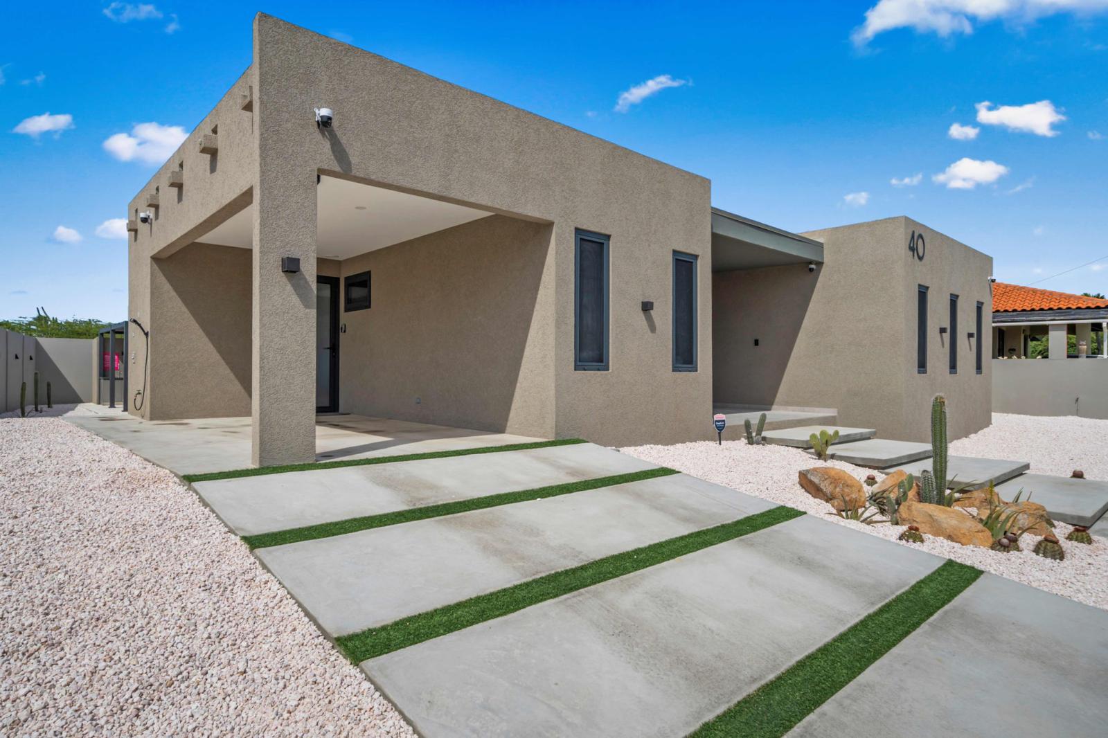 Modern desert style home with sleek architecture & a welcoming entrance - Thoughtfully designed with natural elements & minimal landscaping for a peaceful feel - Private parking and a stylish walkway make arriving at your Aruba retreat effortless