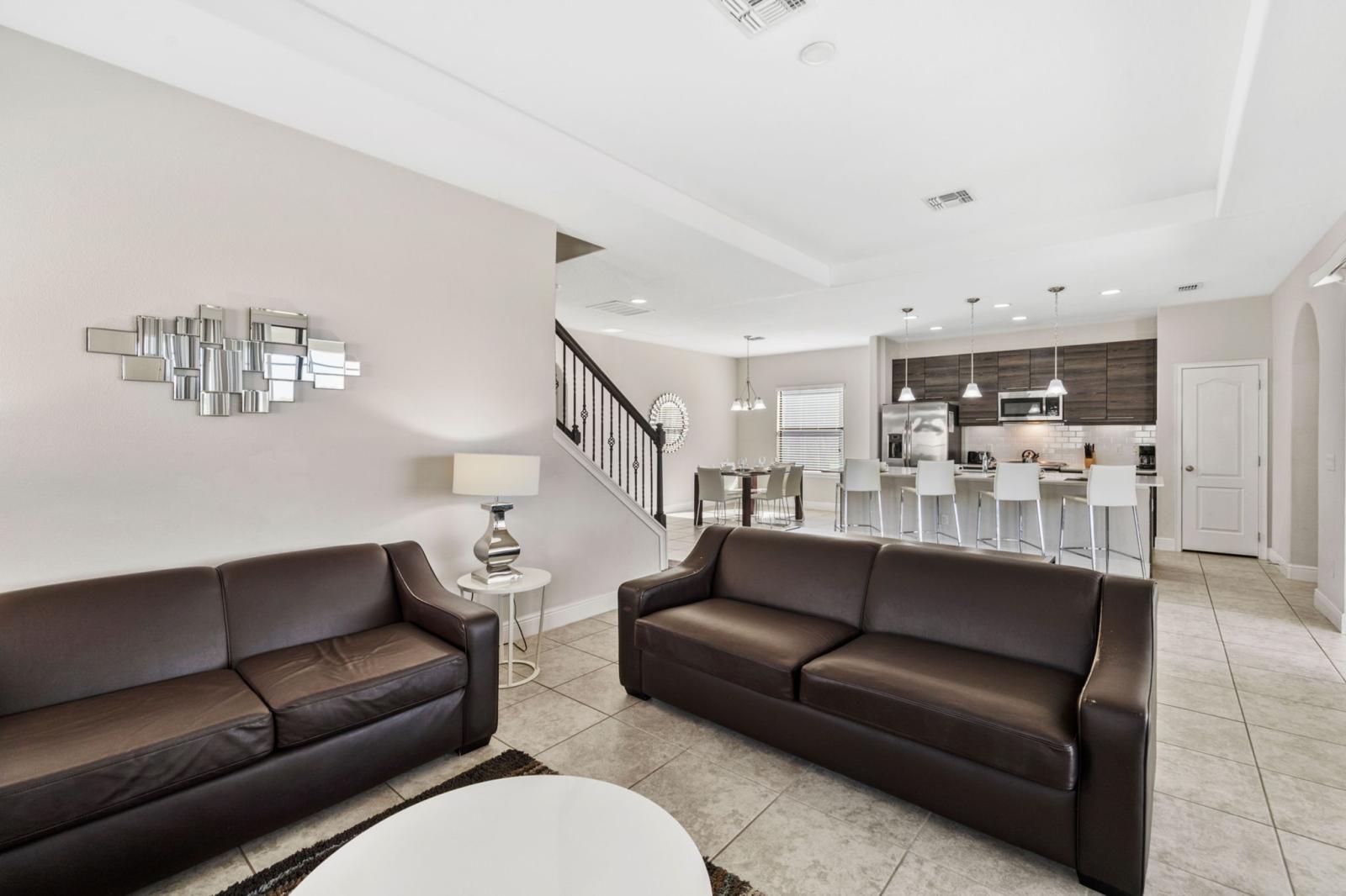 This open-concept living area features a Smart TV, sleek leather seating, and a sofa bed, seamlessly connecting to the modern kitchen—perfect for entertaining!