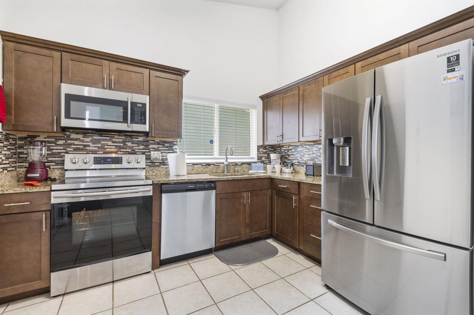 ully equipped kitchen featuring stainless steel appliances, granite countertops, modern tile backsplash, and all the essentials for preparing meals during your stay.