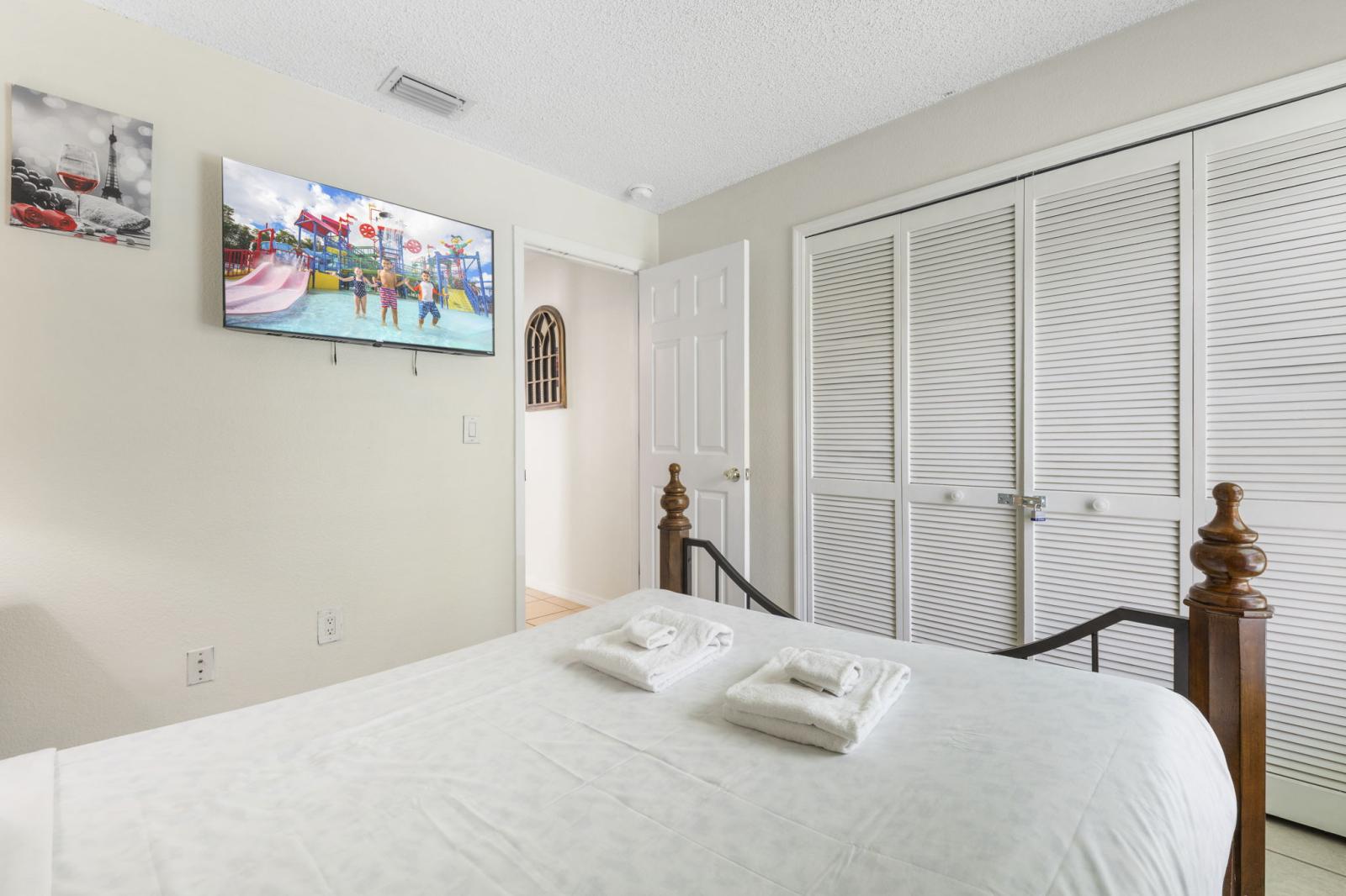 Charming guest bedroom with plush bedding, ample closet space, and a wall-mounted TV—perfect for a cozy night in after a day of fun.