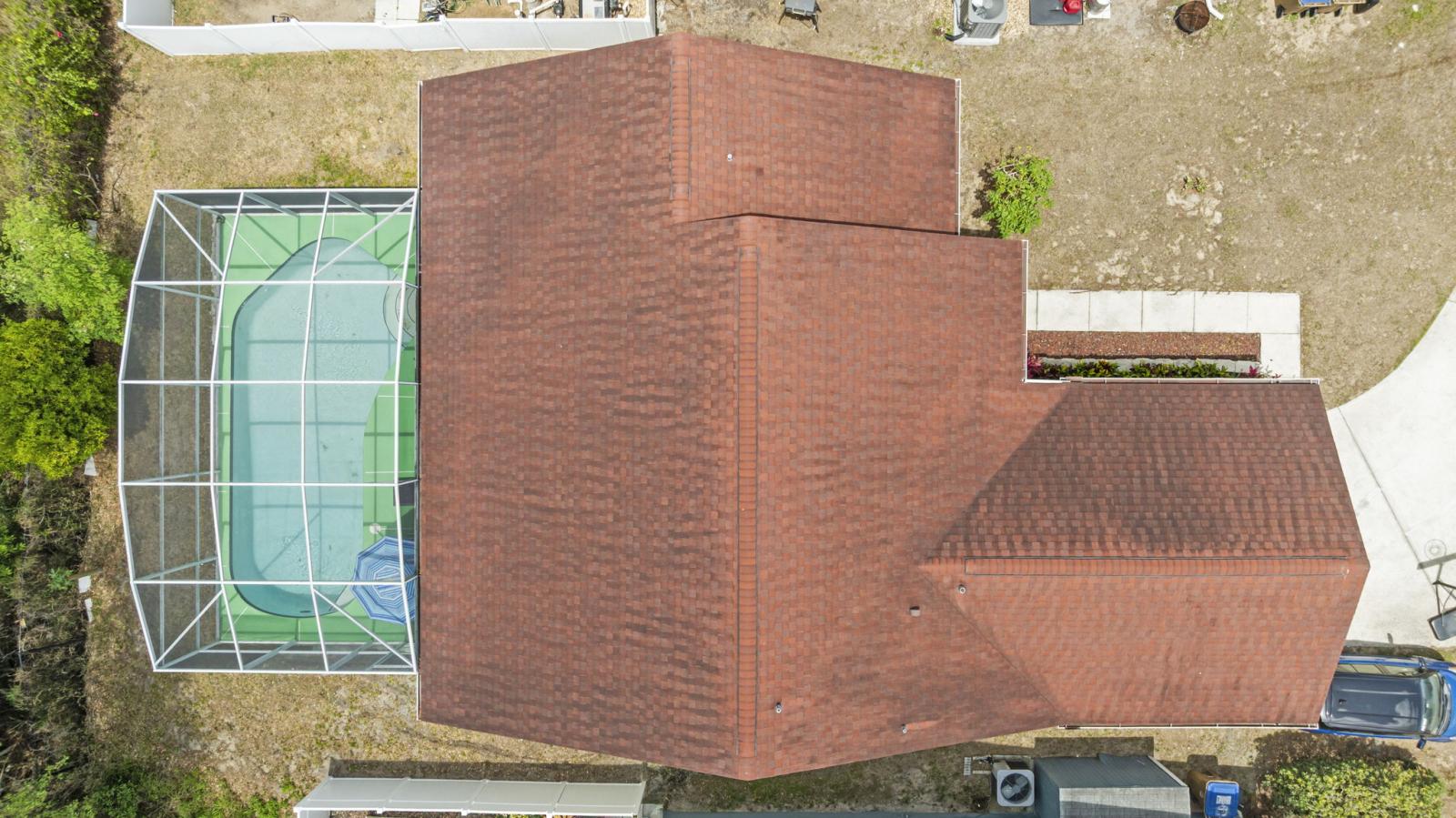 Aerial view of 3016 Bloomsbury Dr showcases the full property layout including the screened-in private pool, expansive roofline, and backyard space — offering a clear perspective of the home's footprint and outdoor features.