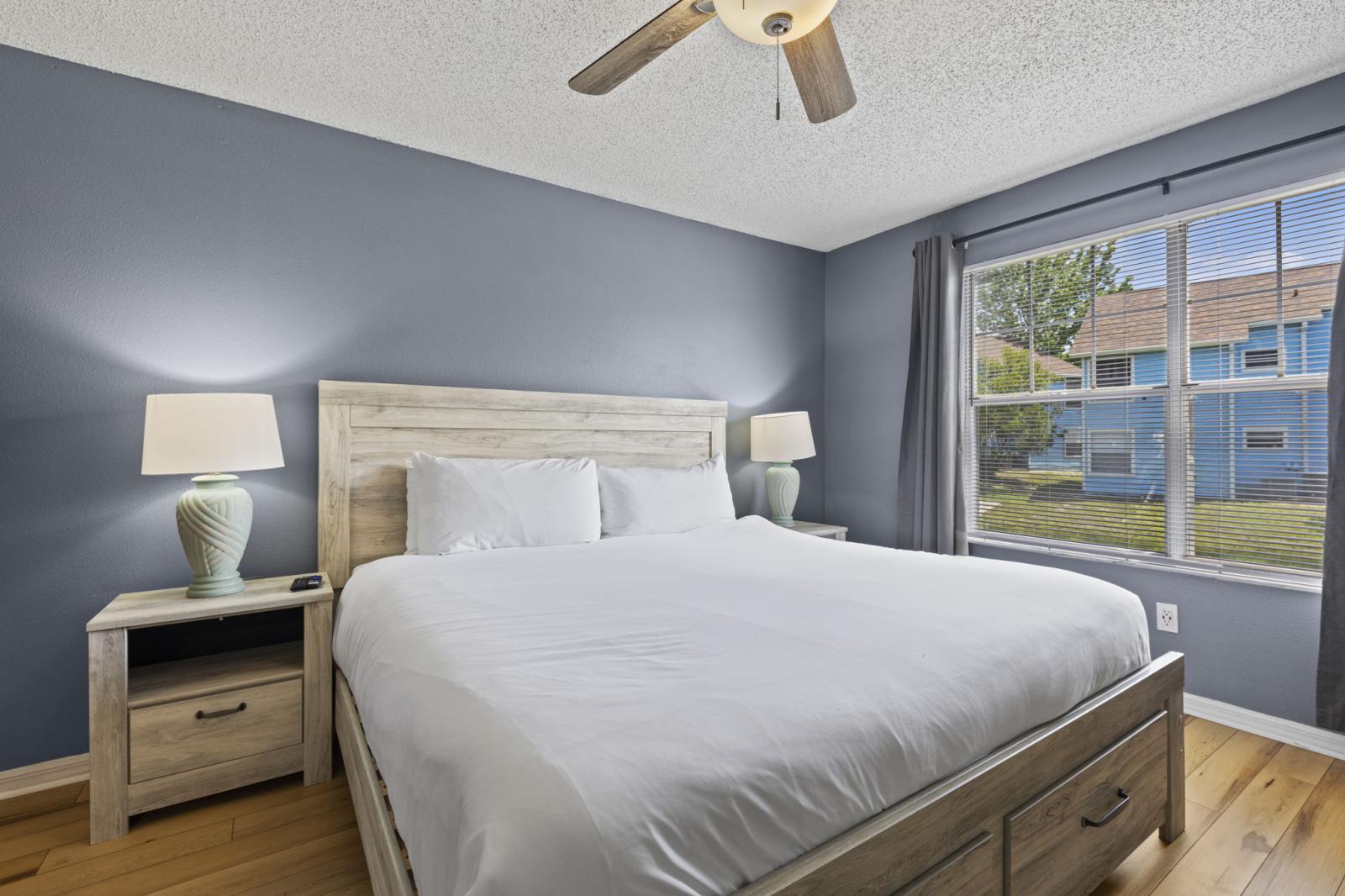🛏️ Primary Bedroom Retreat – Rest easy in the spacious king bed, complete with natural light, bedside lamps, and a ceiling fan for added comfort. Ideal for relaxing after a day at the parks. #KingSuite #MasterBedroom #VacationRest
