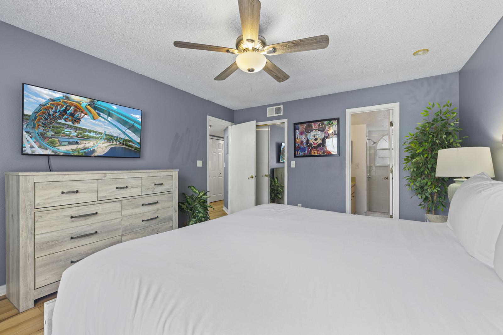 📺 King Suite Comfort – Unwind with your favorite shows on the smart TV or step into the en-suite bathroom after a day of exploring. This spacious primary bedroom includes dresser storage and a ceiling fan for added comfort. #MasterSuite #SmartTV #VacationE