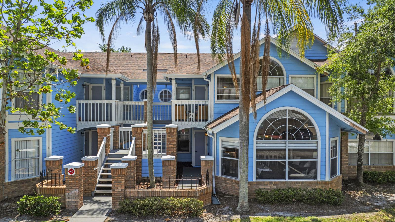 🏡 Charming Resort-Style Exterior – Welcome to your Florida getaway at The Villas at Somerset. This bright, blue-painted building with tropical landscaping and private entrance sets the tone for your stay. #VacationVibes #FloridaStay #TheVillasAtSomerset