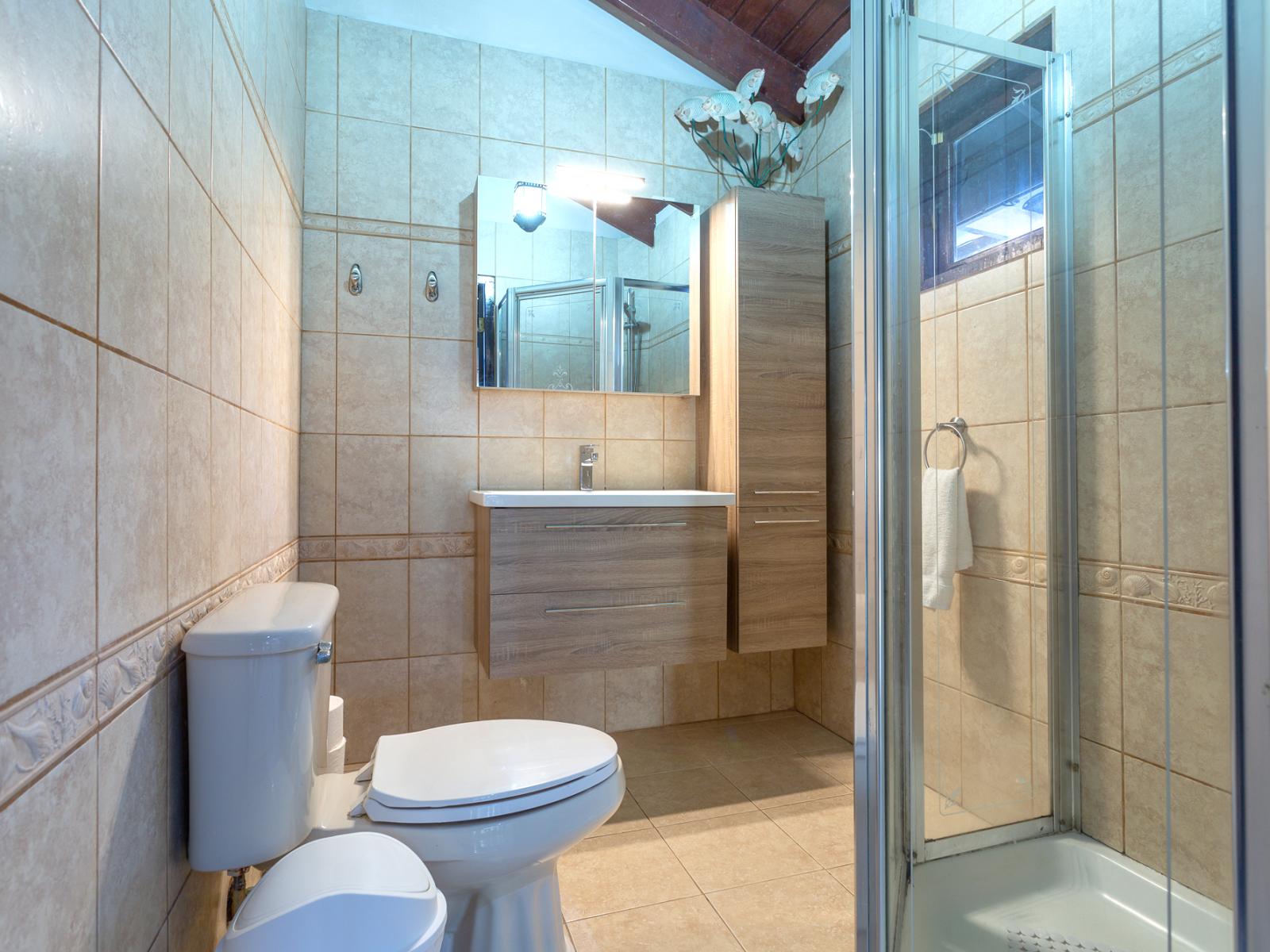 Classy Bathroom of the apartment in Noord Aruba - Beautiful Vanity with large size wall mirror - Sufficient storage space - Neat and clean toilet seat - Availability of all bathroom amenities - Stunning glass cabin shower area