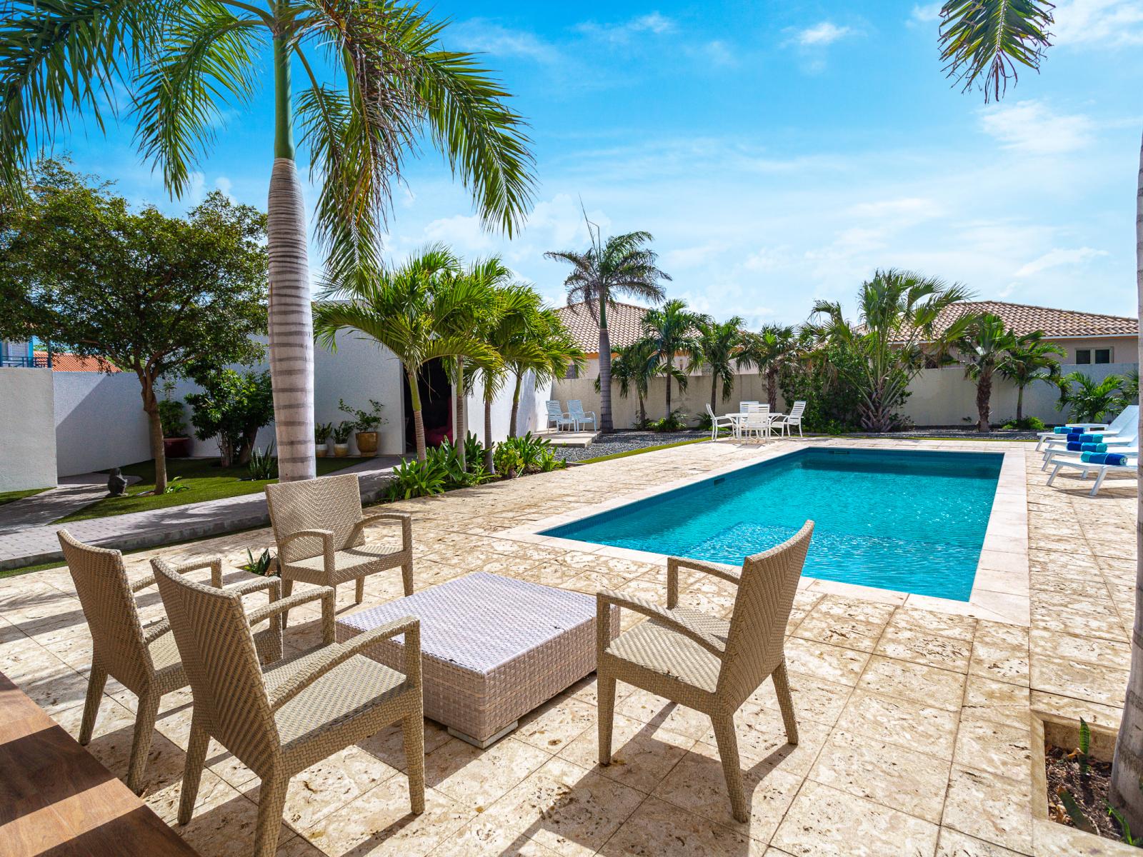 Lush Private Pool Area of the villa in Noord Aruba - Cozy sitting Arrangements - Crystal clear water - Palm trees and tropical Plants for enhancing vacation feel