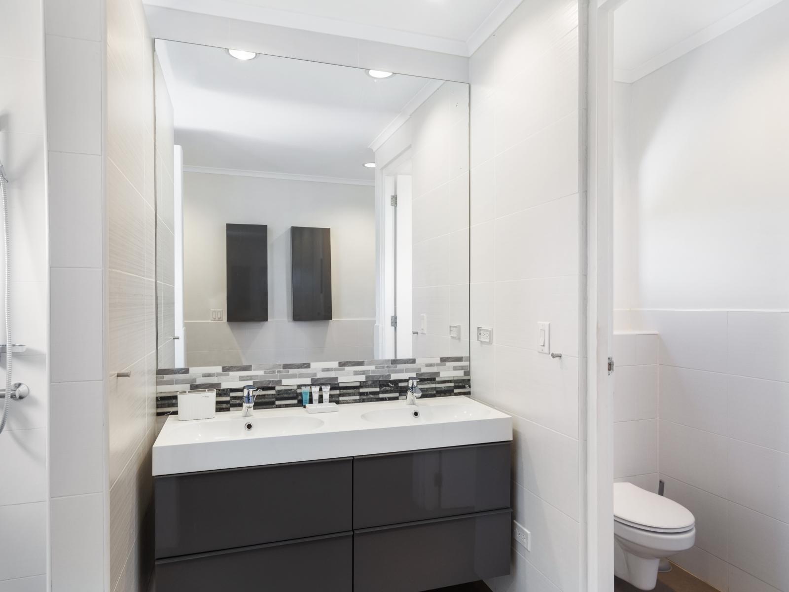 Lush Bathroom of the Villa in Noord Aruba - Chic design featuring a sleek vanity and upscale lighting - Understated elegance with clean lines and refined details - Ample natural light highlighting the elegant tile work