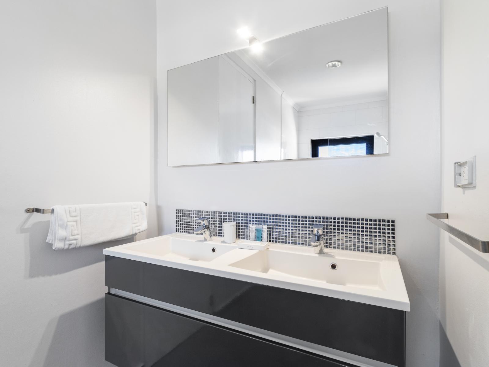 Relax in Bathroom 3, featuring a double sink, a toilet, and a walk-in shower for a modern touch.