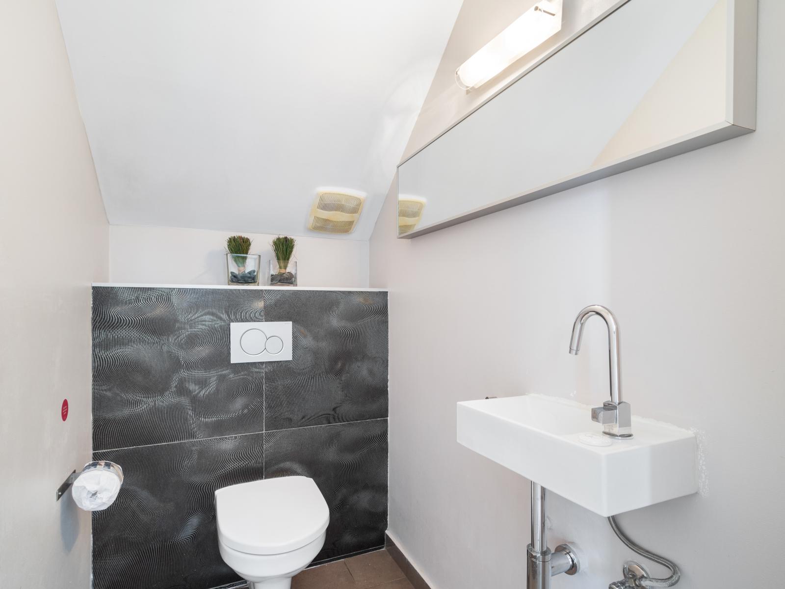 Perfect for quick stops, our half bathroom features contemporary fixtures and a sleek design.