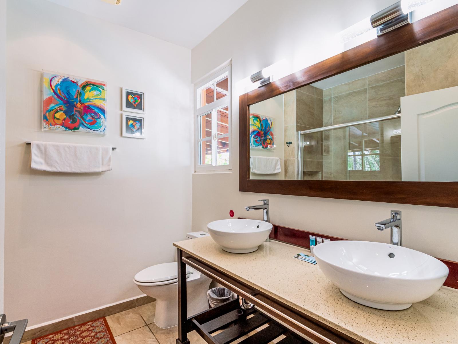 Main Bathroom 1 features a double vanity, toilet, and a spacious walk-in shower, ensuring comfort and convenience during your stay.