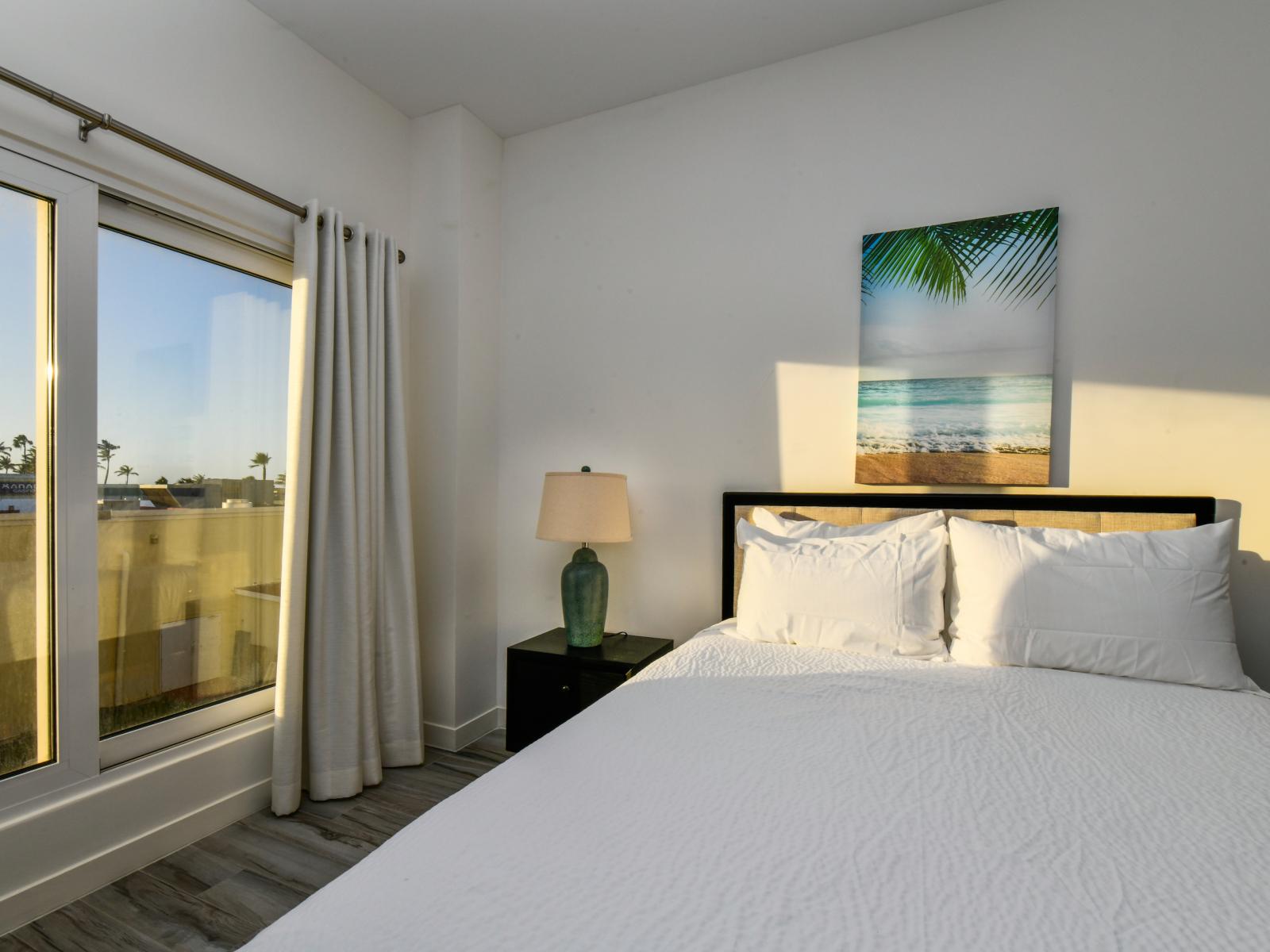 Deluxe Bedroom of the 2BR condo in Noord Aruba - Full King Size Bed - Minimalist decor, creating a clean and uncluttered sleeping space - Cozy retreat with a plush bed, perfect for relaxation - Soft, lighting for a tranquil mood