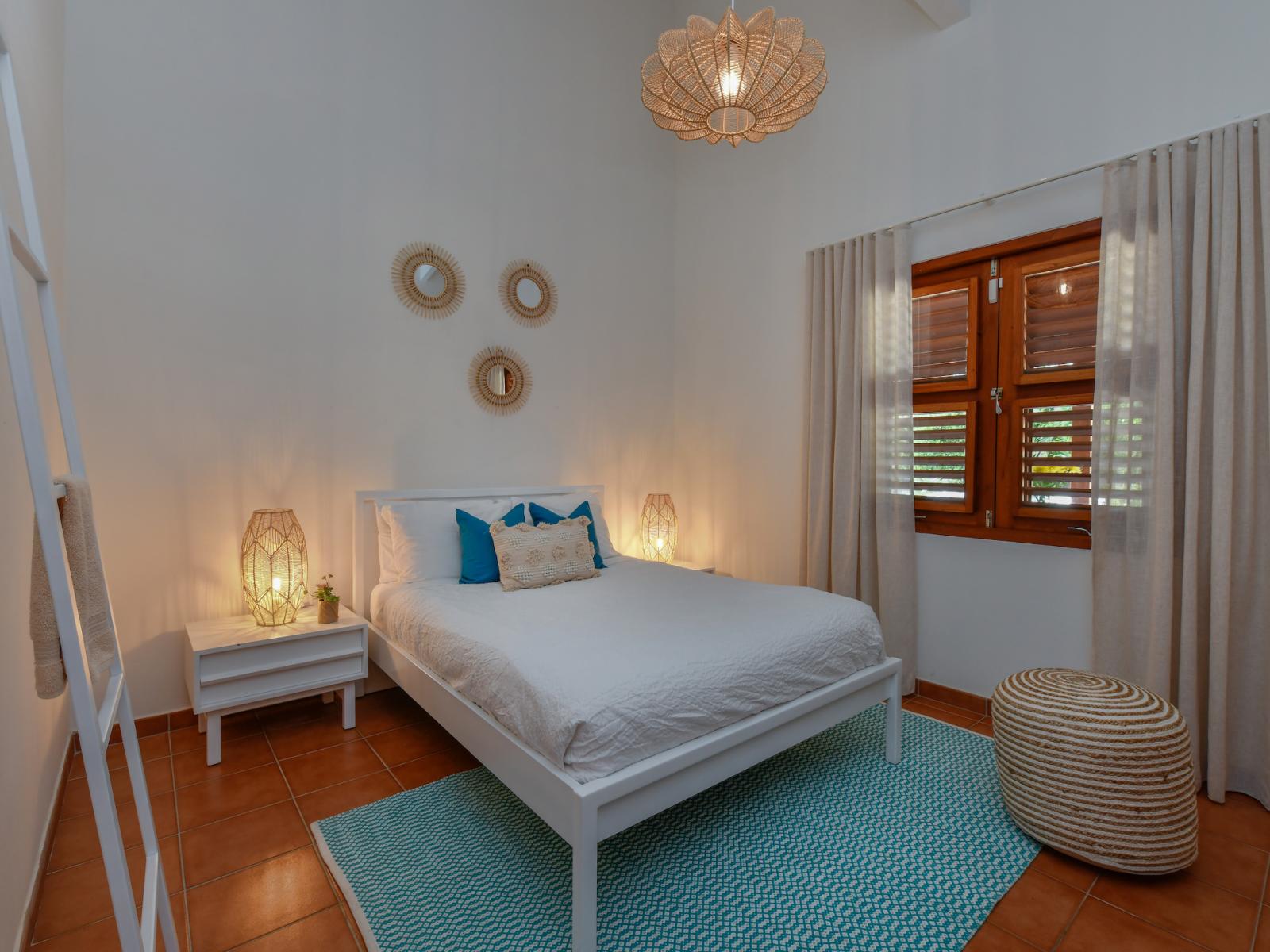 Glorious bedroom of the villa in Noord, Aruba - Comfy king size bed - Elegantly designed room beautifully decored with large aesthetic wall paintings - Majestic table lamps and elite chandelier - Neat and clean linen with soft pillows