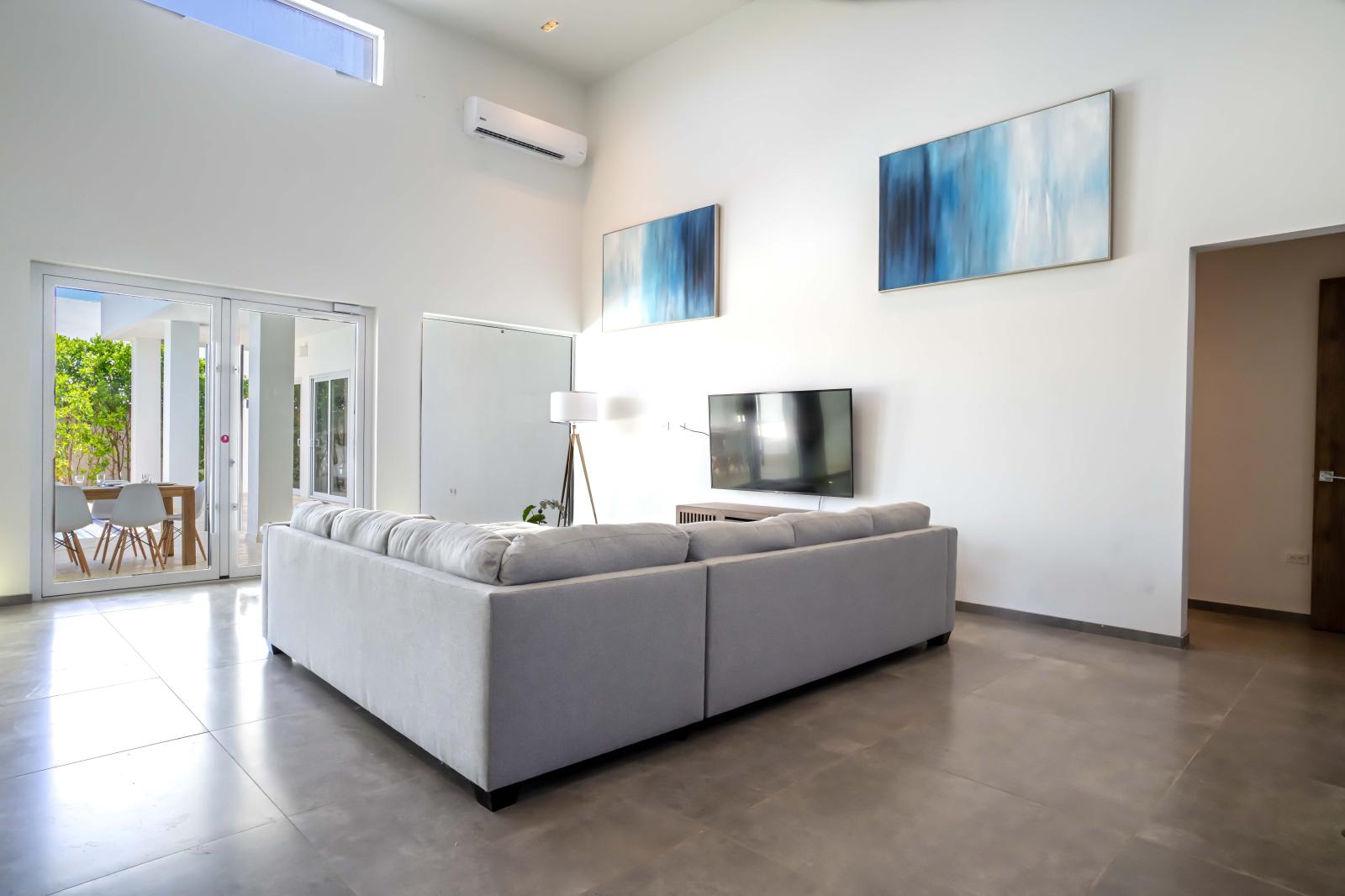 Living room provides a wall-mounted flat-screen television and a glass-top coffee table