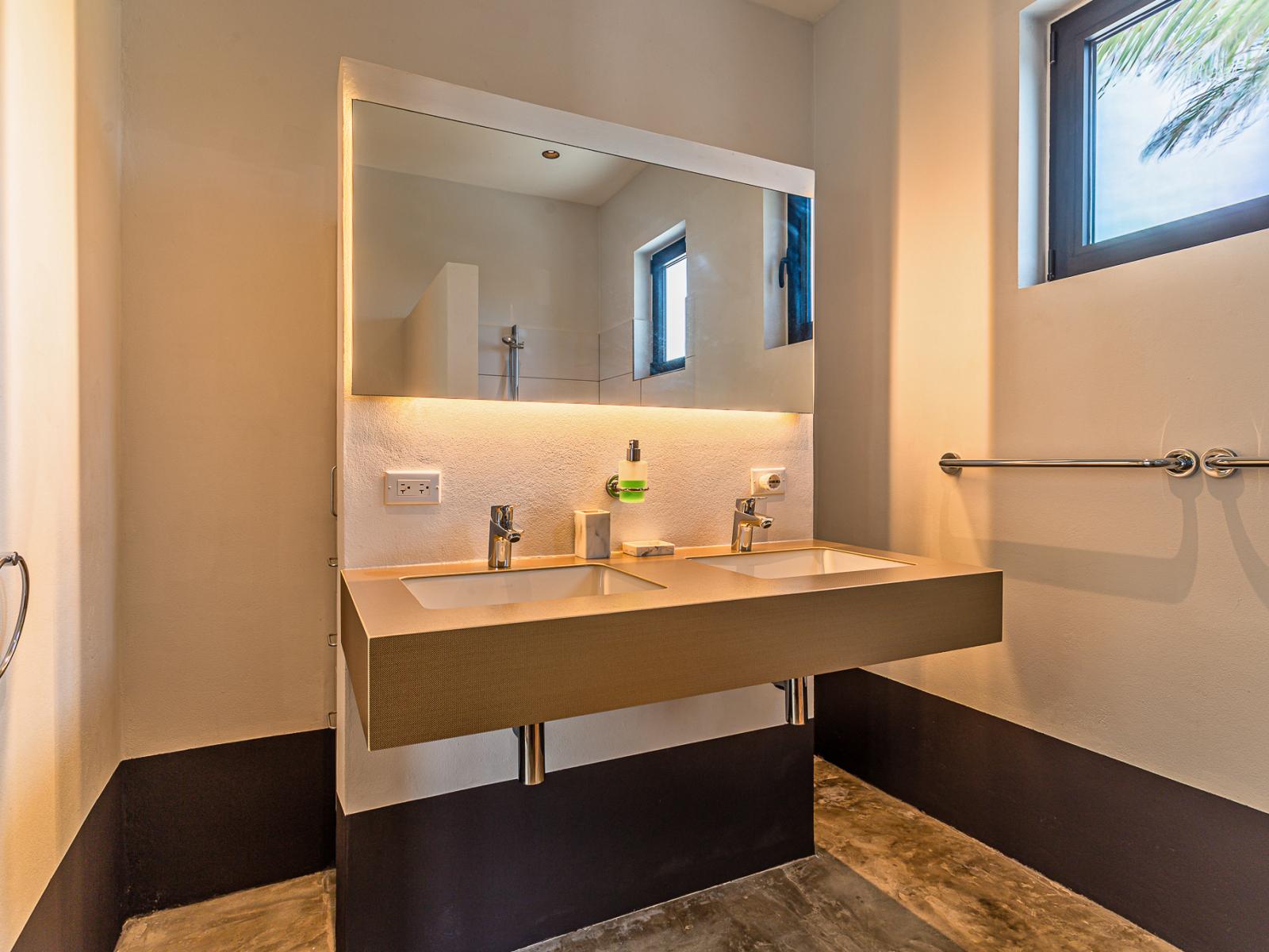 Bathroom 1 features a modern double vanity, a toilet and a walk in shower