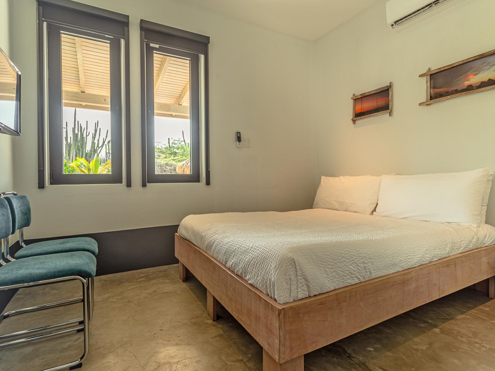 Enjoy Bedroom 2 with its Queen bed, wall-mounted flat-screen TV, and picturesque view of the backyard and pool.