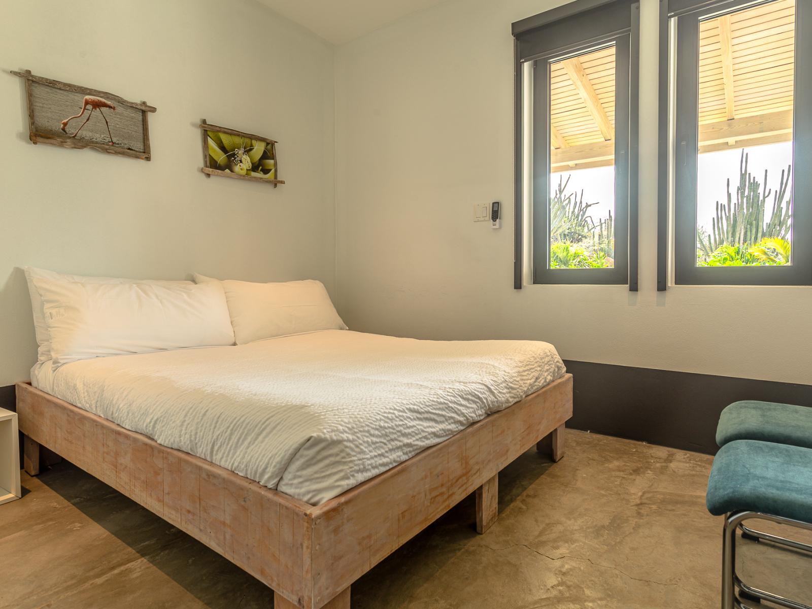 Relax in Bedroom 4 with a Queen bed, wall-mounted flat-screen TV, and stunning views of the backyard and pool area.