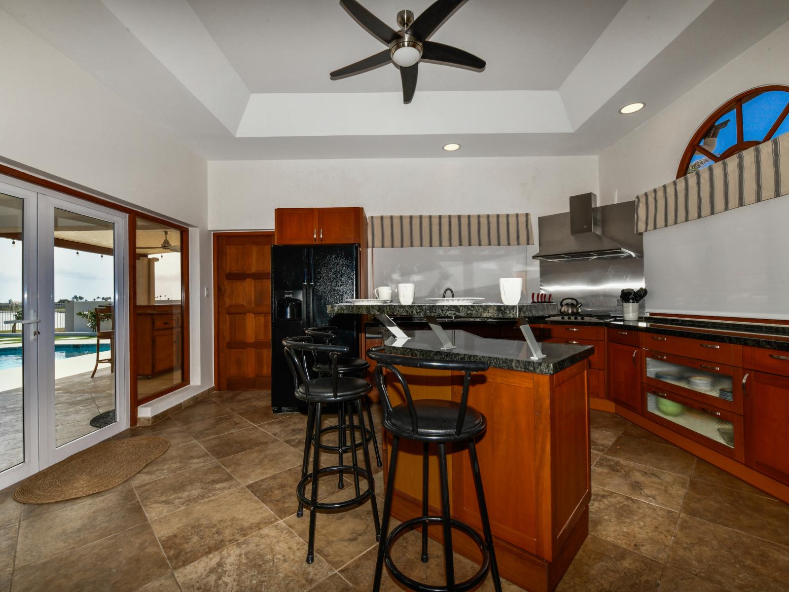 Magnificent Kitchen Area of the 3BR House in Noord Aruba - Well-lit space with strategically placed task lighting - Breakfast bar with high chairs - Natural light streaming in, enhancing the overall ambiance